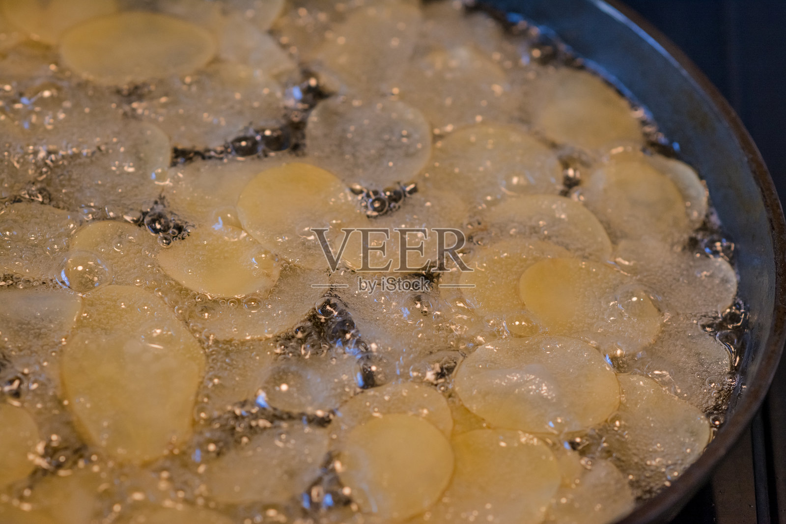 切好的土豆在热油沸腾的锅里照片摄影图片
