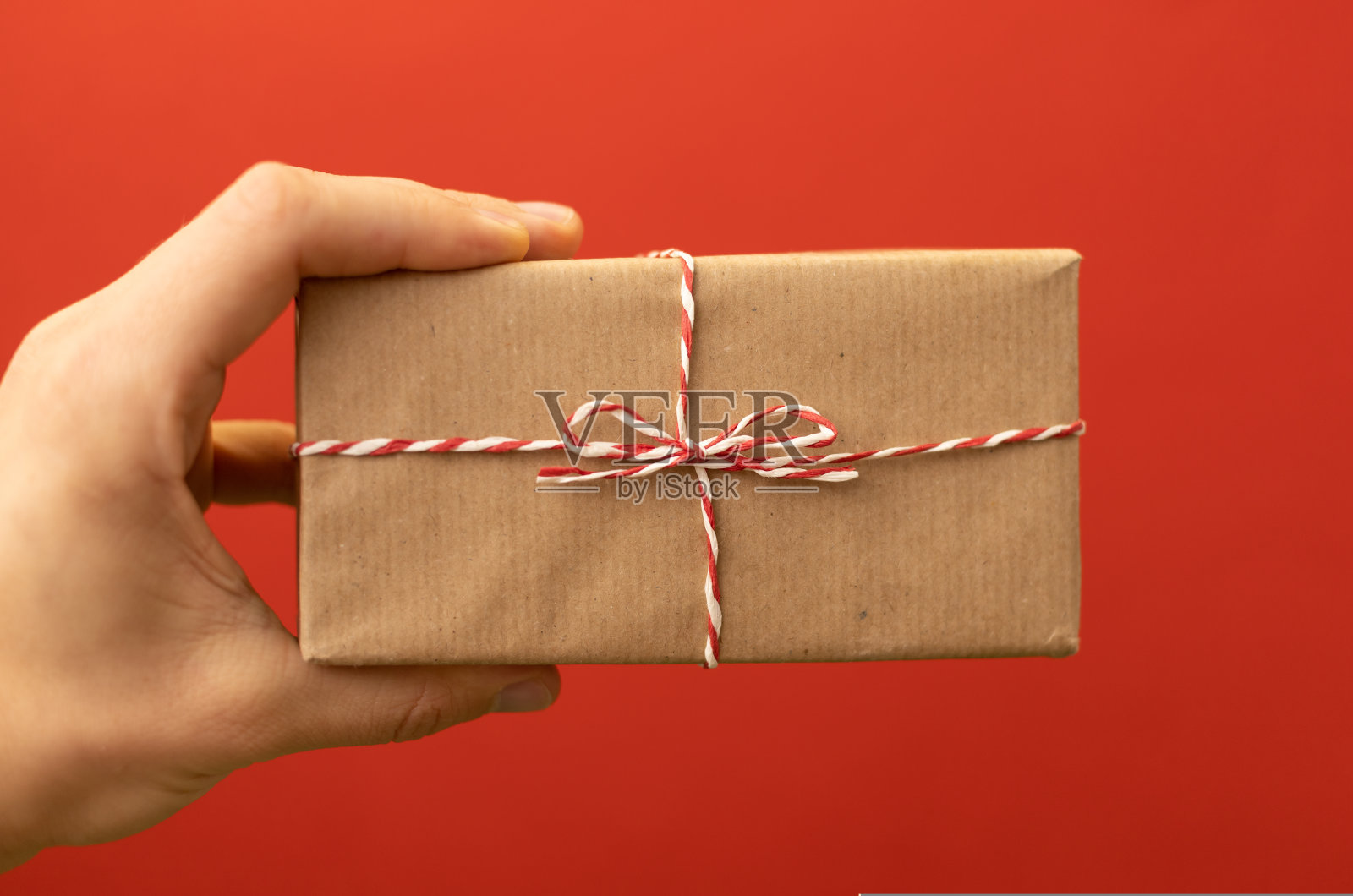 手握手工包装的礼物在红色的背景照片摄影图片
