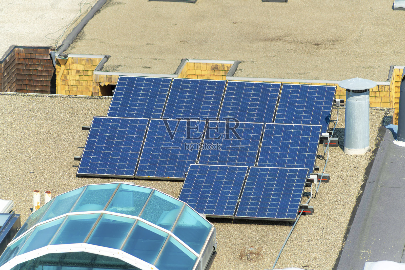 阳光照射下的黑色太阳能电池板在平坦的碎石屋顶中午照片摄影图片