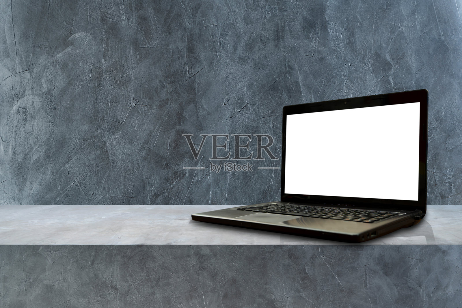 一台笔记本电脑被放置在阁楼的混凝土架子上。在一个黑暗的阁楼背景和显示照片摄影图片