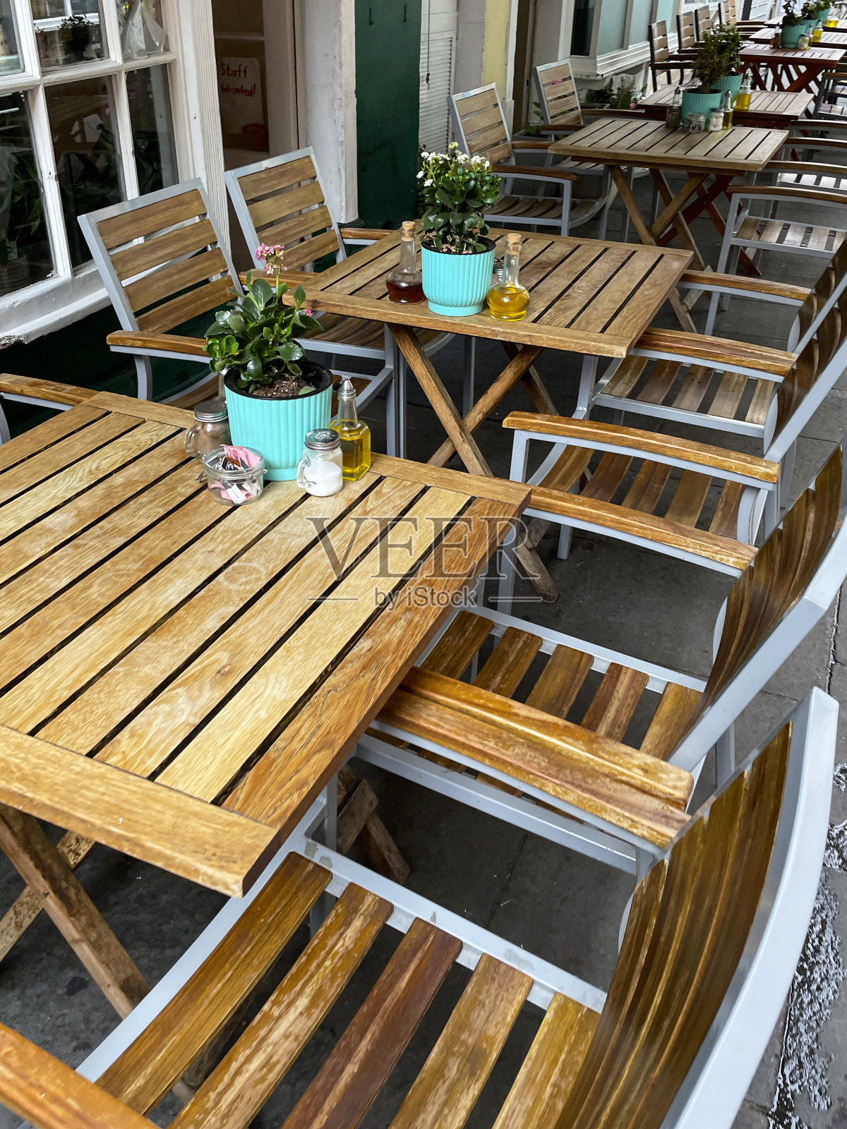 路边餐厅外的金属和木制花园露台桌椅的形象，人行道上的咖啡馆露天餐厅，盆栽植物和cruet集在桌面，重点在前景照片摄影图片