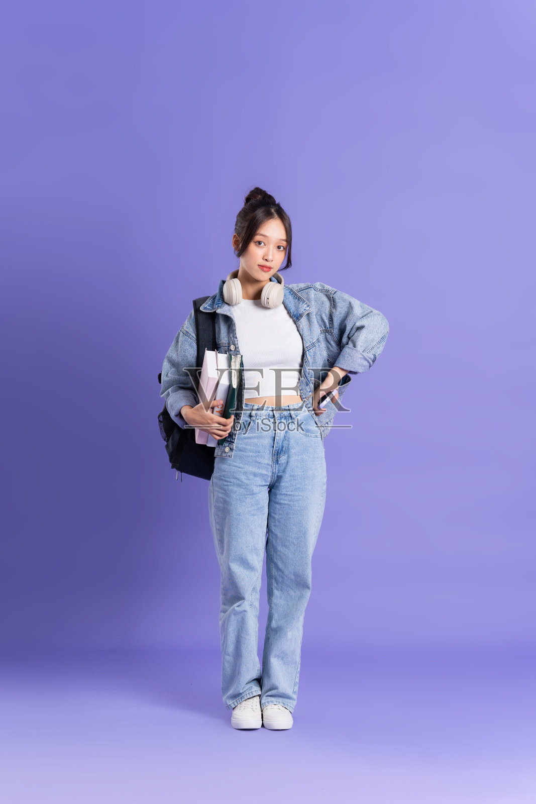 一个美丽的亚洲女学生穿着紫色背景背包的肖像照片摄影图片