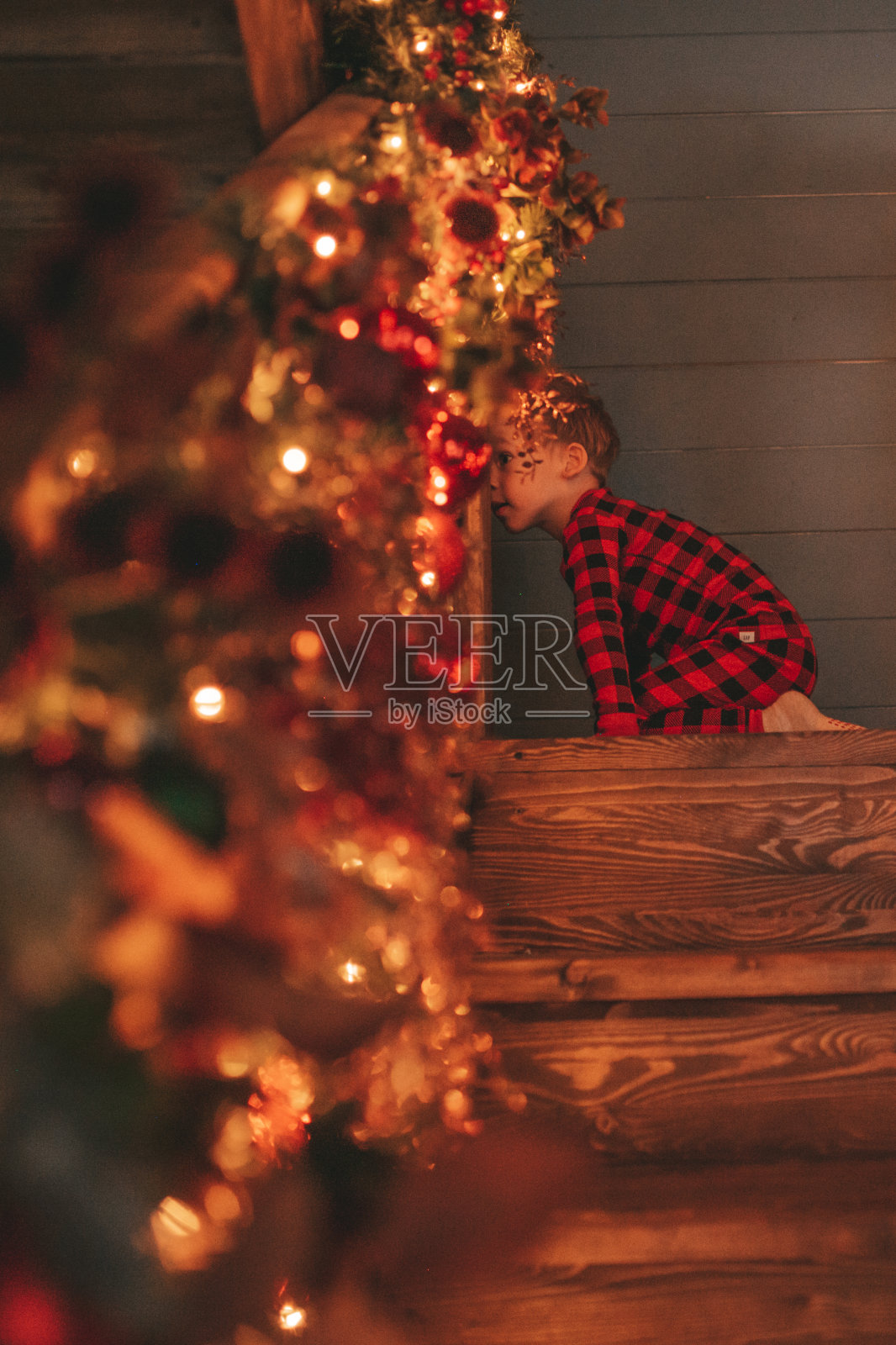 真诚真实的快乐微笑小男孩在红色格纹睡衣愚弄在小屋圣诞装饰照片摄影图片