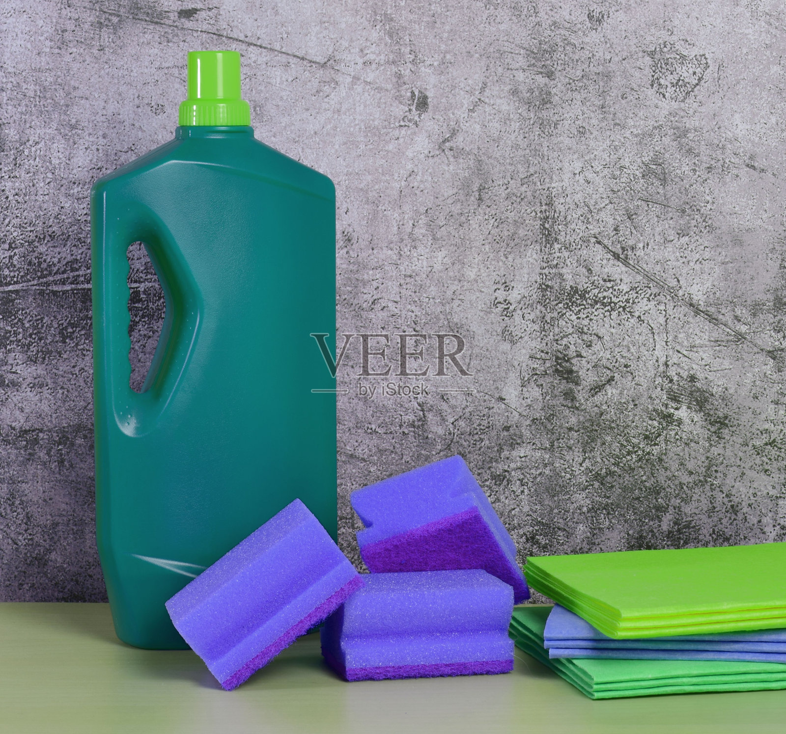 一套清洁产品放在灰墙前的桌子上照片摄影图片