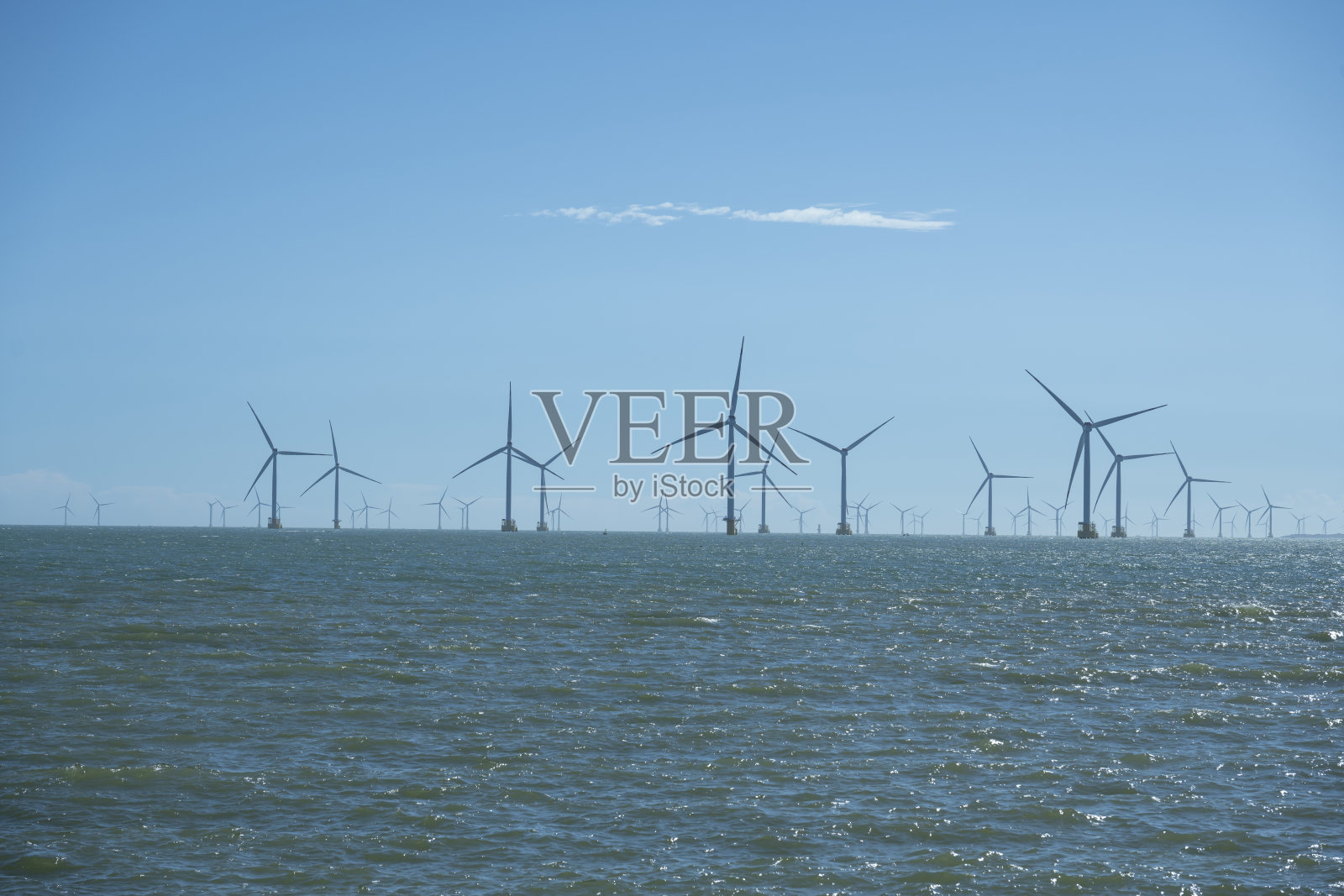 风平浪静的大海后面是风力发电站照片摄影图片