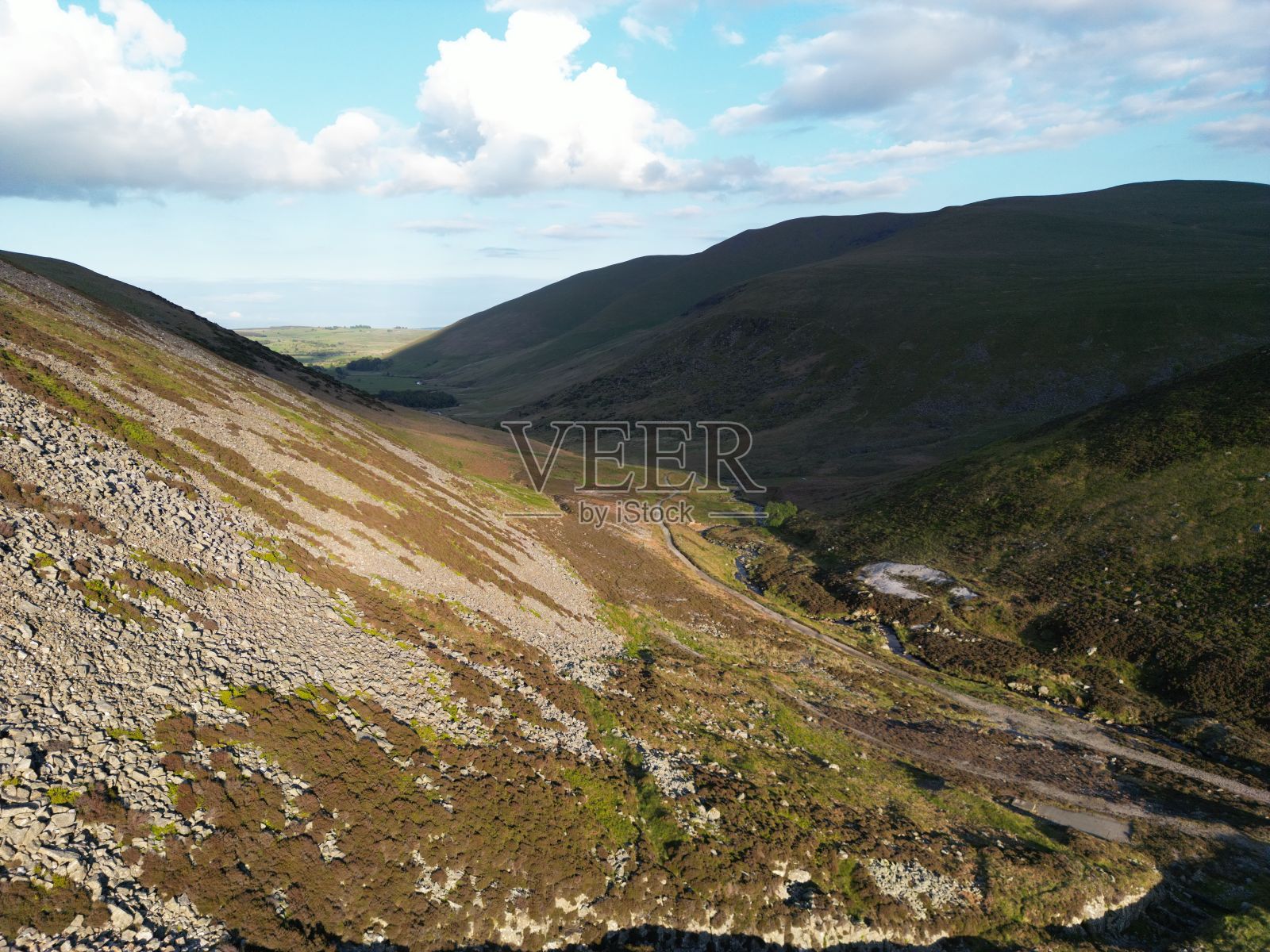在阳光明媚的日子里，蜿蜒的丘陵草原照片摄影图片