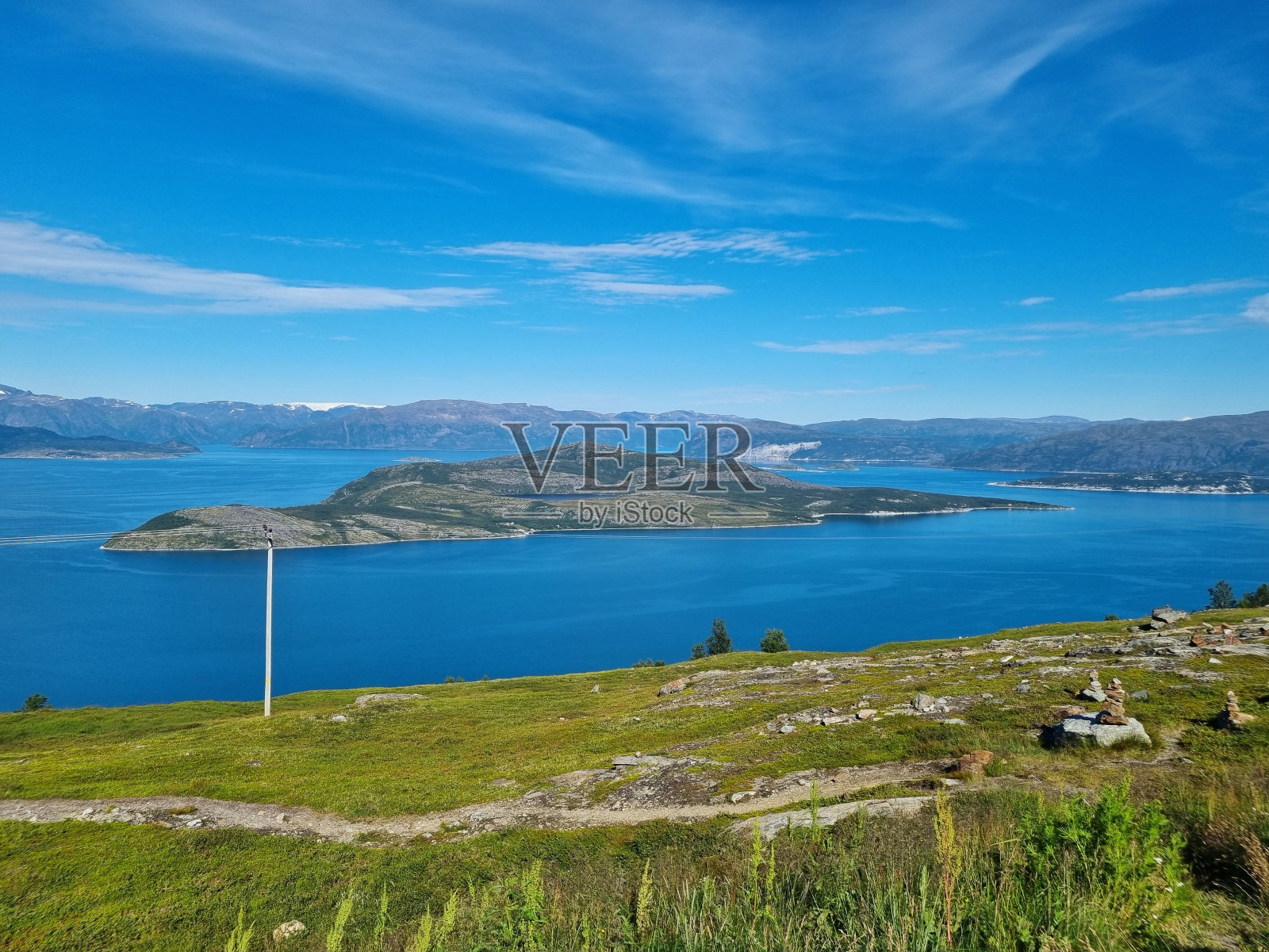 在挪威的一个阳光明媚的日子里，一个湖泊与山脉和多云的蓝天的美丽风景照片摄影图片