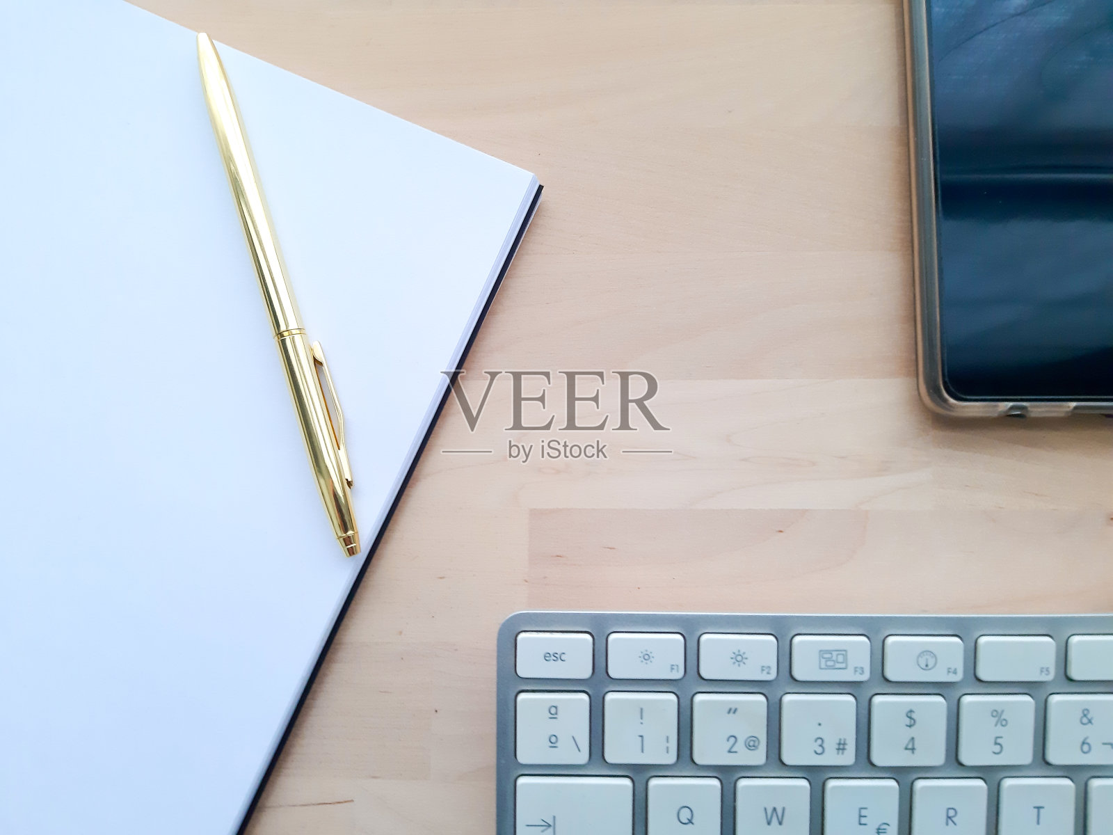 办公桌配有办公配件，办公器物放在木桌上。

居家办公办公桌办公室，电脑，智能手机，白色和金色的钢笔在木桌上照片摄影图片