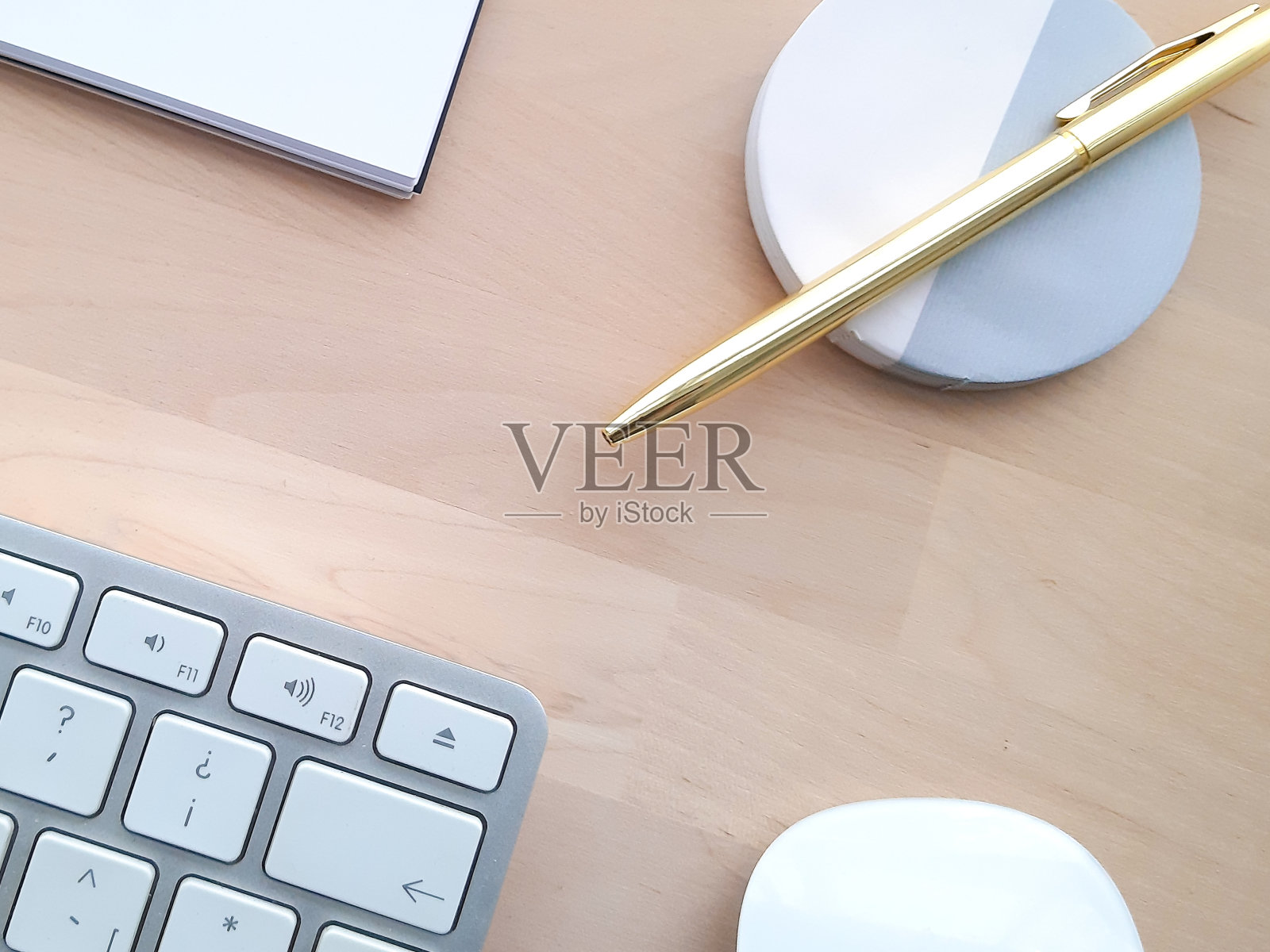 办公桌配有办公配件，办公器物放在木桌上。

居家办公办公桌办公室，电脑，智能手机，白色和金色的钢笔在木桌上照片摄影图片