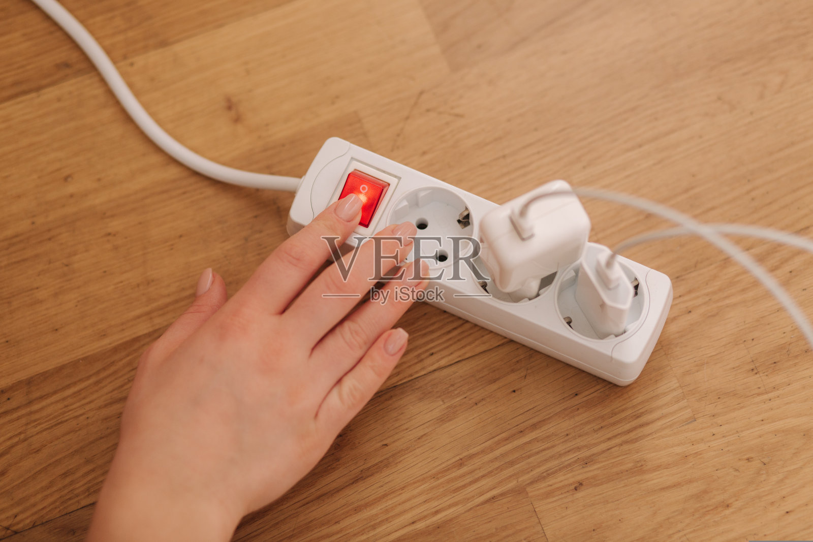 女性在家打开延长线的俯视图。白色电缆连接器照片摄影图片