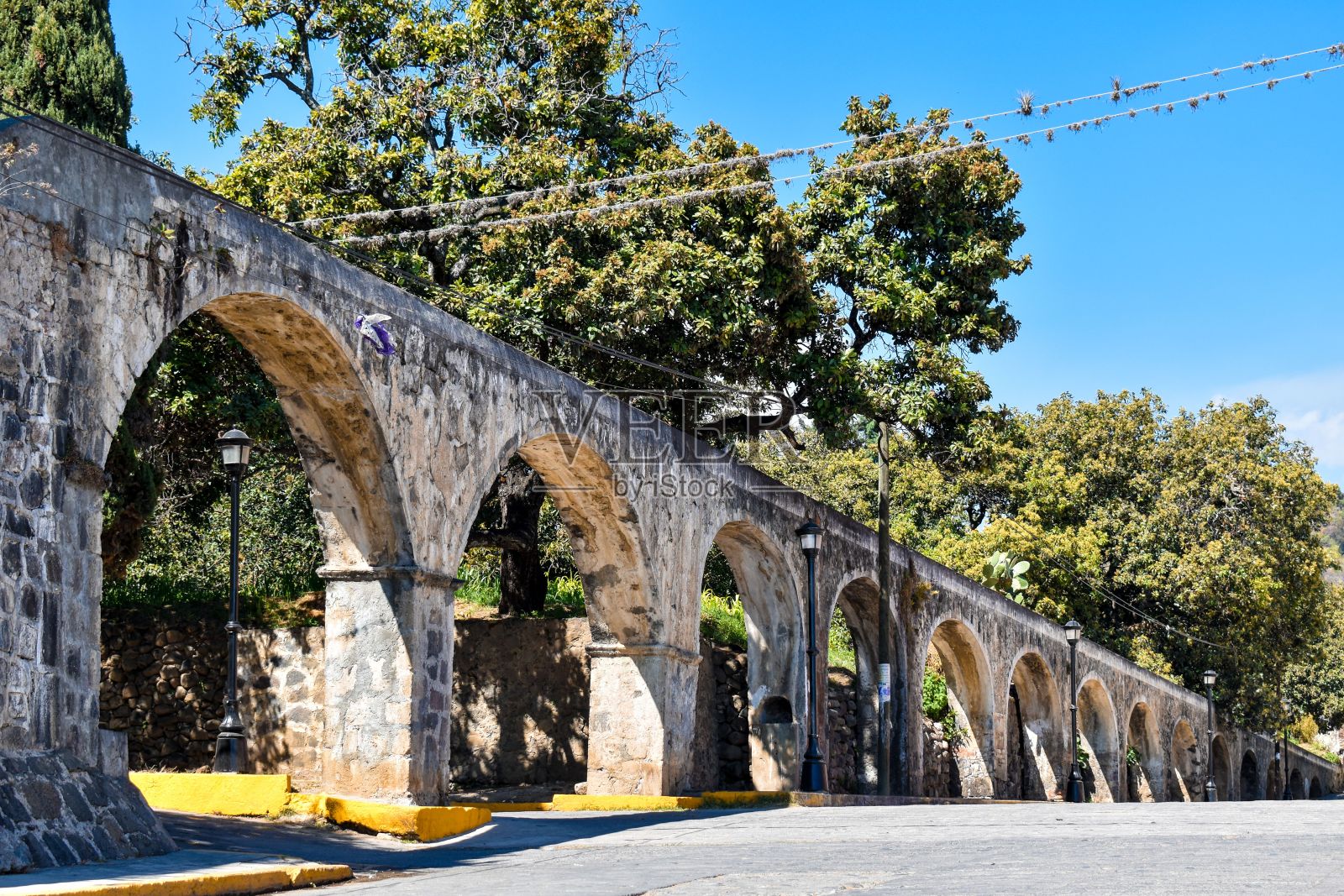 古老的引水渠，后面是街道，前面是绿树照片摄影图片