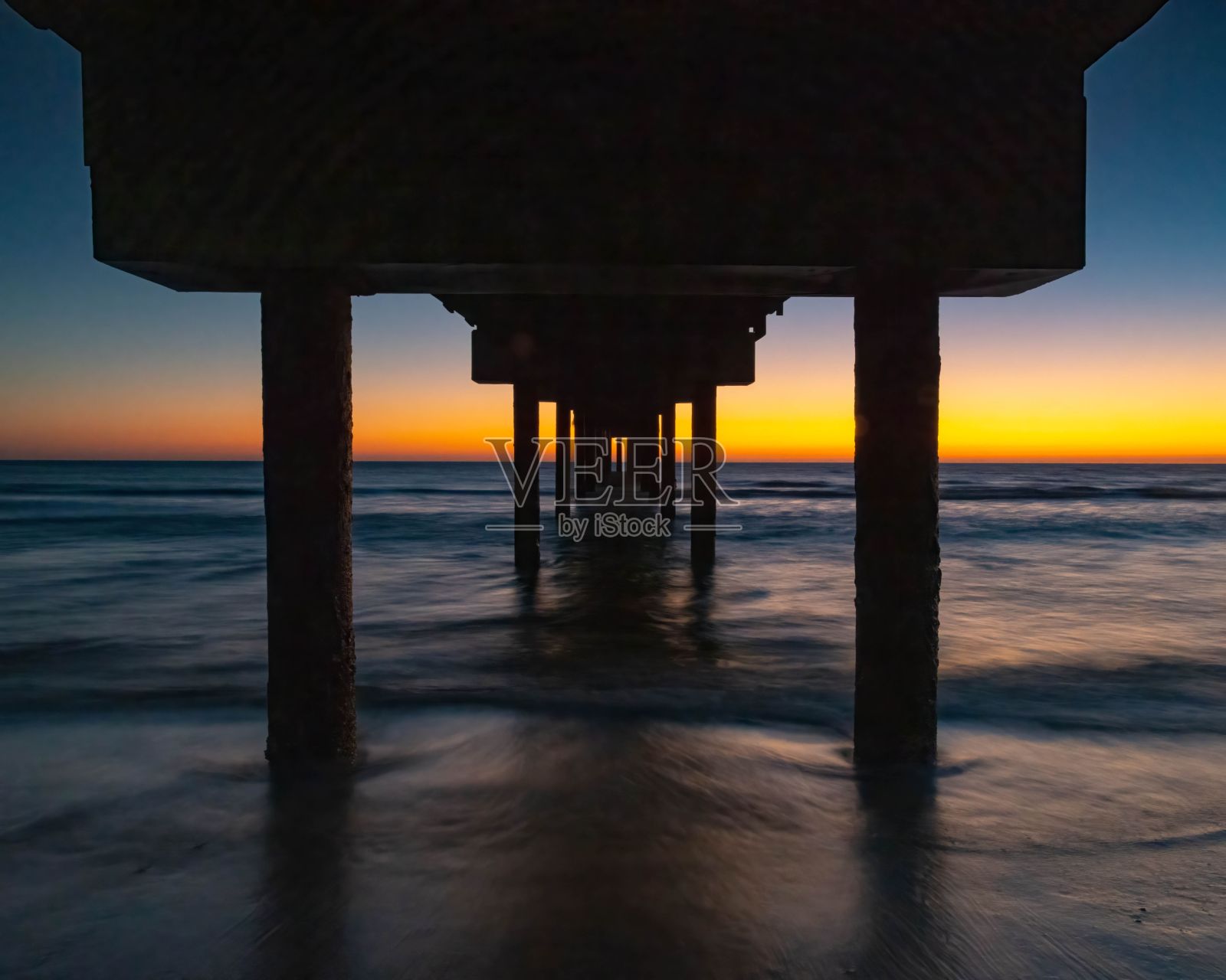 日落时分，在海上一座剪影桥下拍摄的美丽照片照片摄影图片