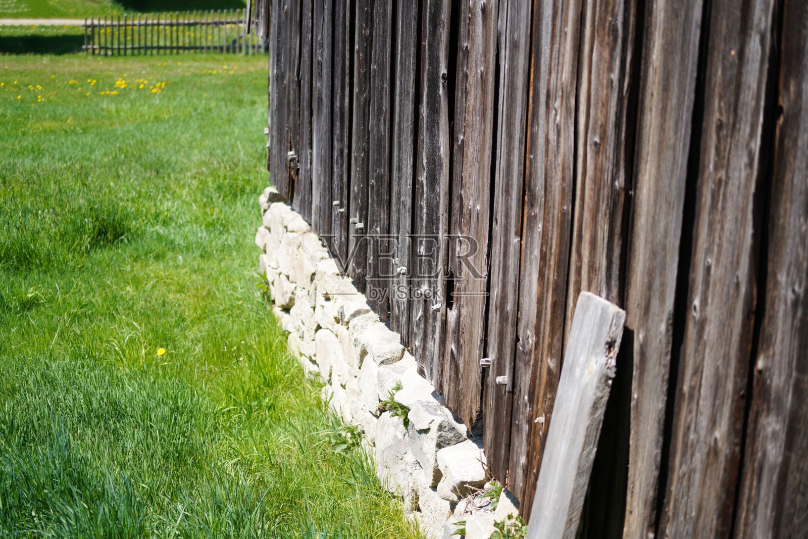 近距离的一个木制栅栏与石头在绿色领域照片摄影图片