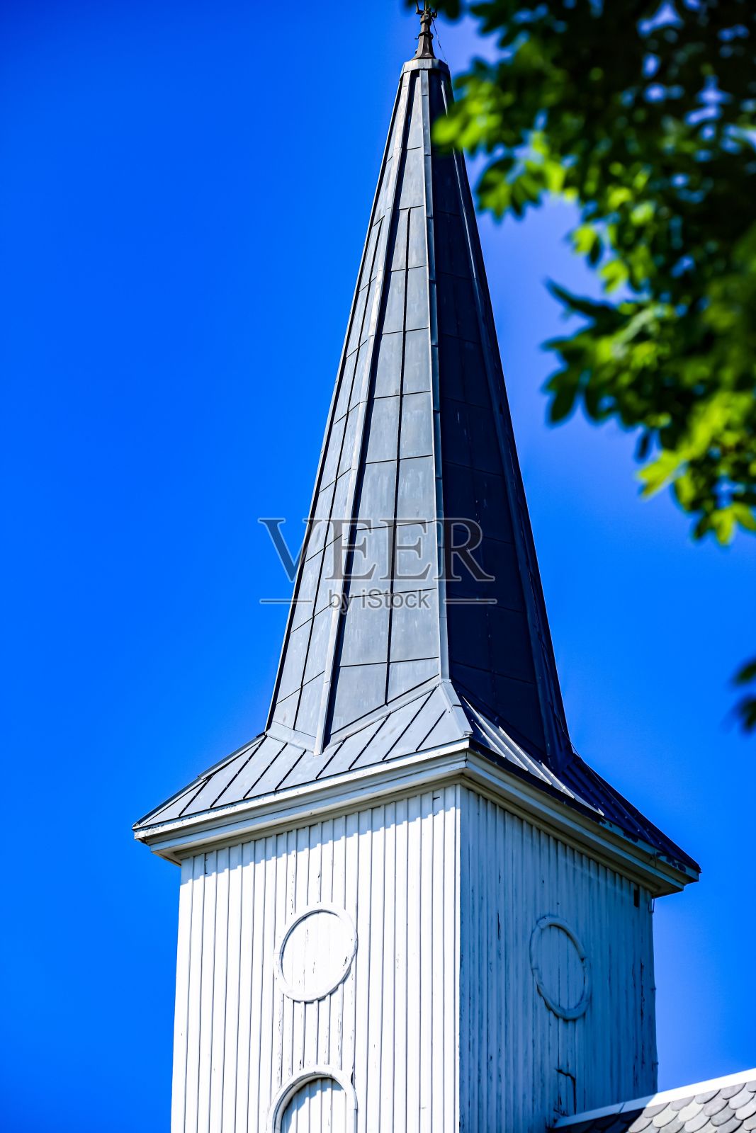 在湛蓝晴朗的天空中，垂直拍摄了一座建筑的塔楼。照片摄影图片