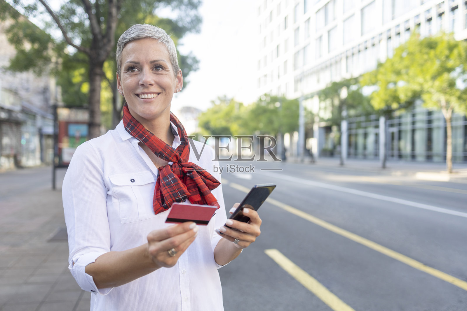 快乐的女人短发站在街上和网上购物照片摄影图片