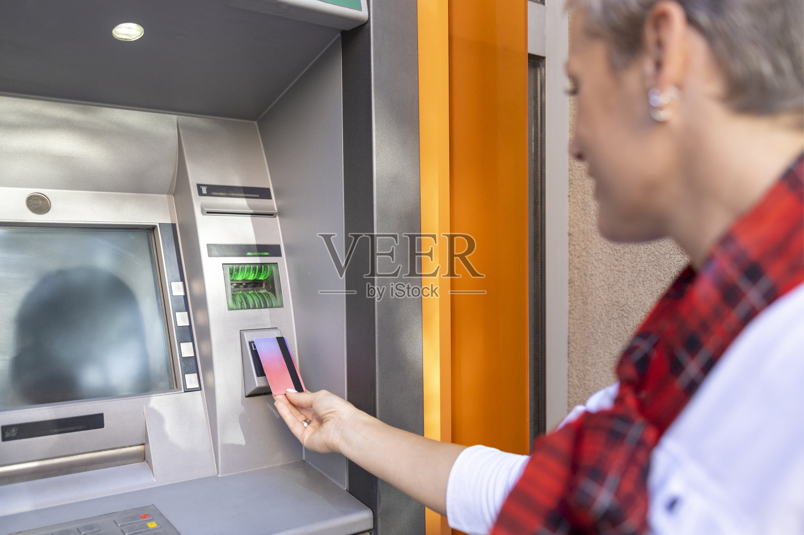 年轻女子站在自动取款机前使用信用卡照片摄影图片