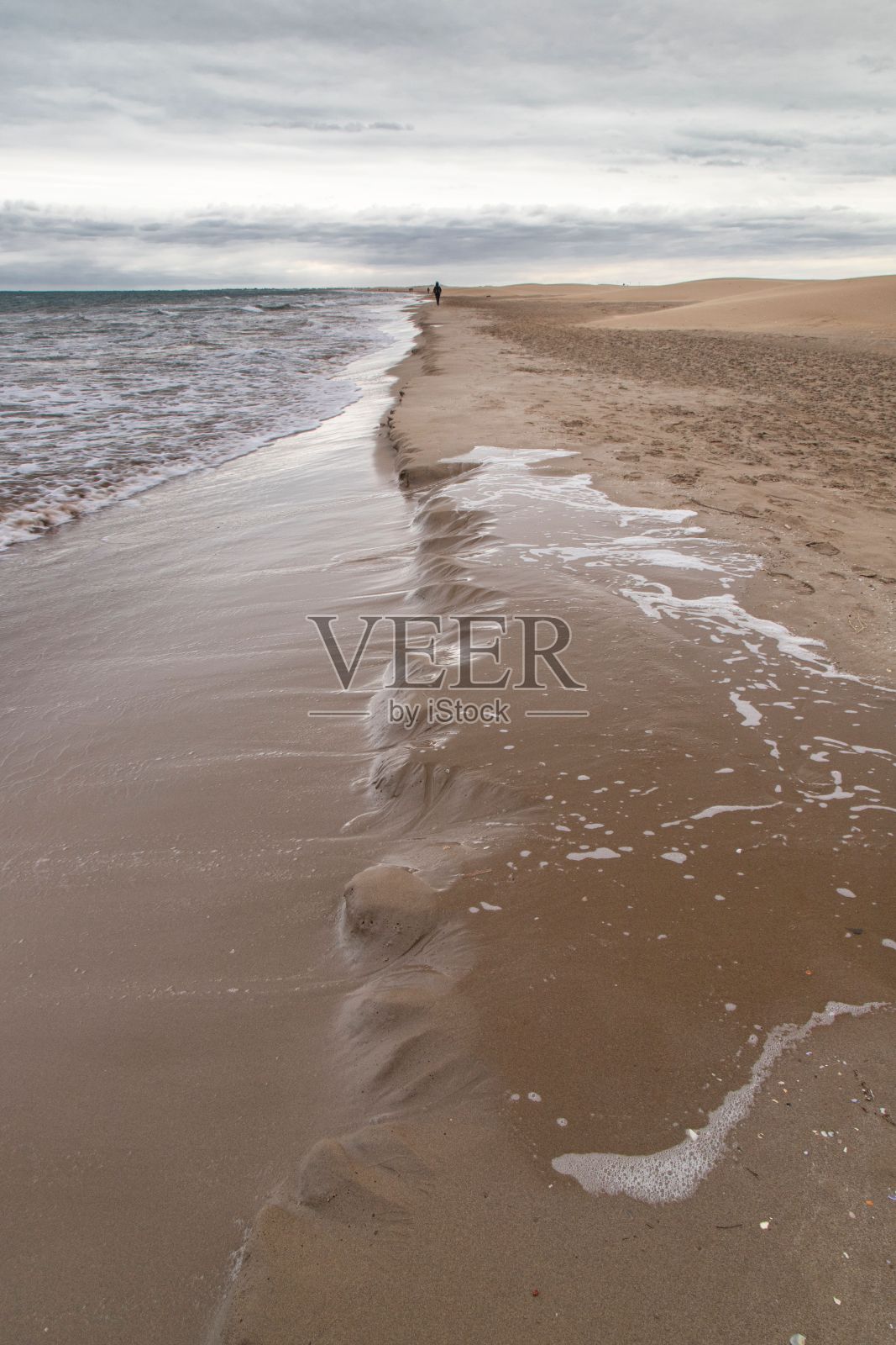 在多云的天空下，海浪到达沙滩的垂直视图照片摄影图片