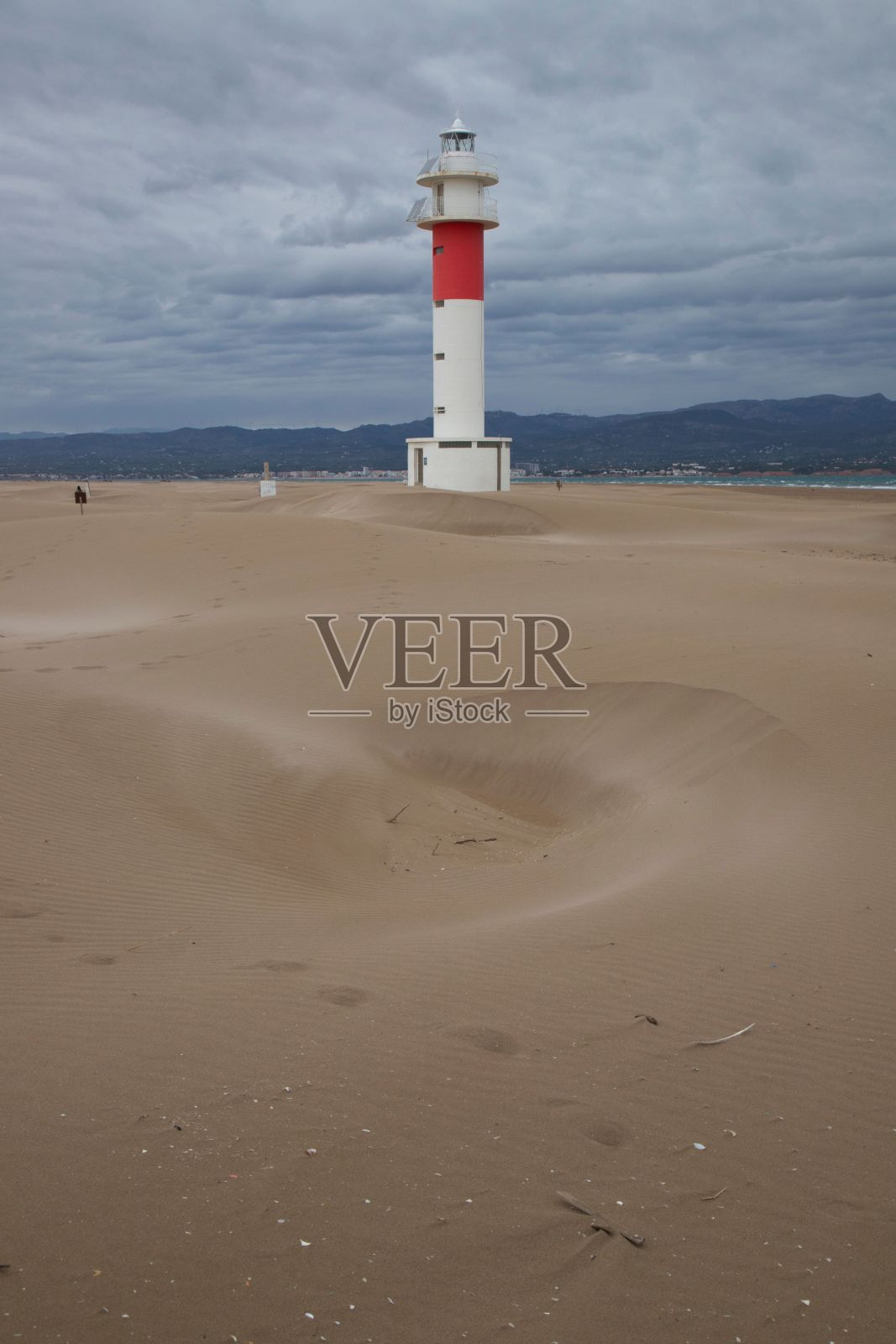 在多云的天空下，沙滩上的灯塔的垂直视图照片摄影图片