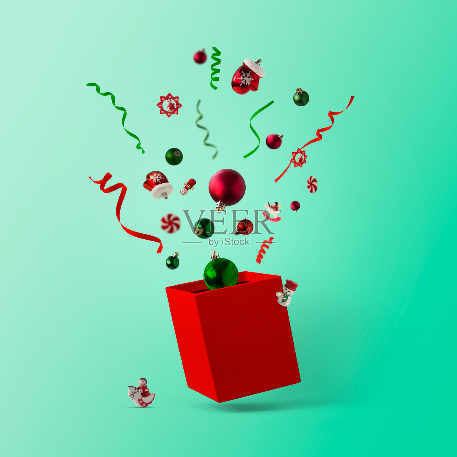 绿色和红色的圣诞小玩意和装饰品在空中飞舞，跳出盒子，映衬着绿色的背景;创意圣诞布局，贺卡，最小的新年购物照片摄影图片