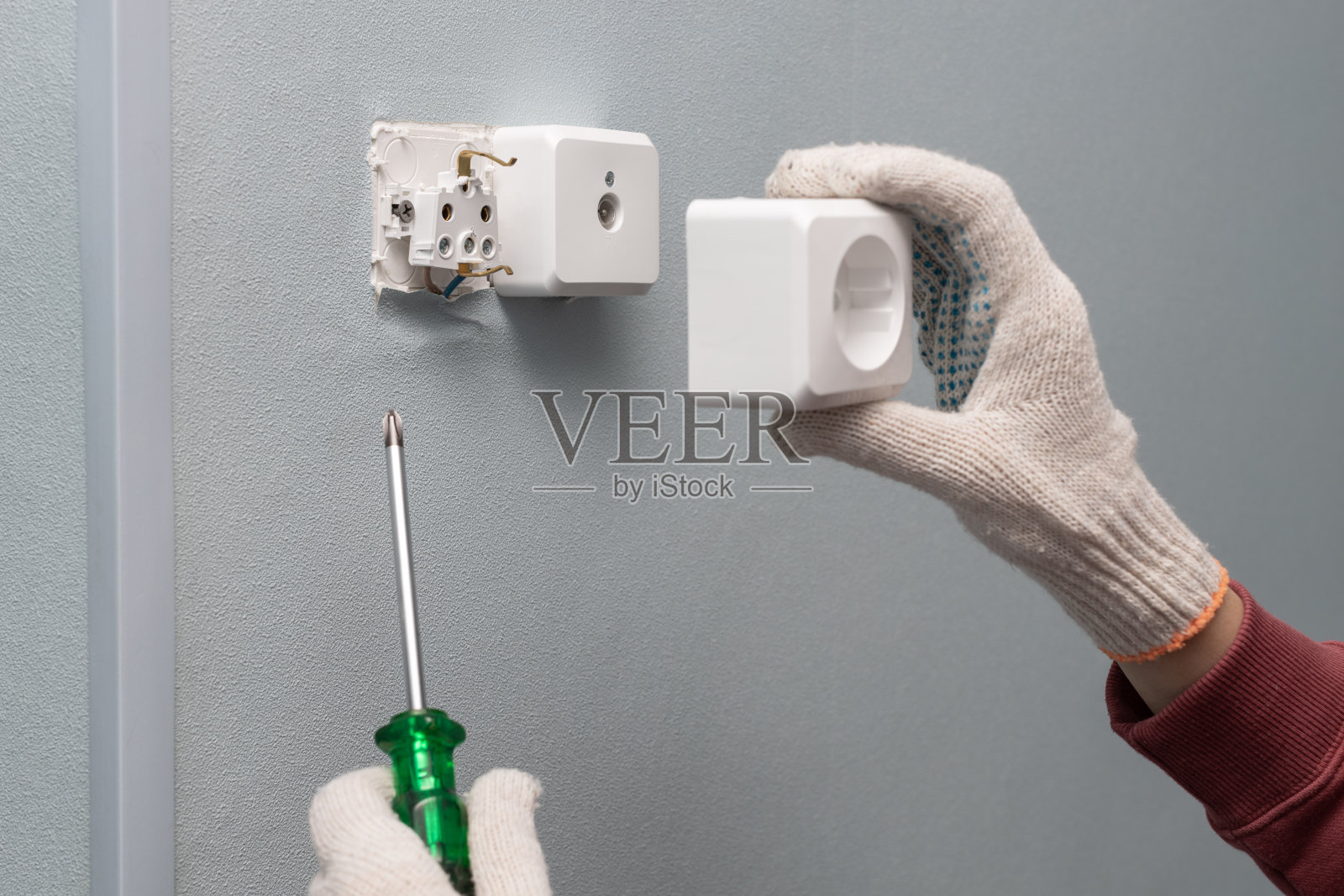 一名男子用螺丝刀修理电源插座。照片摄影图片