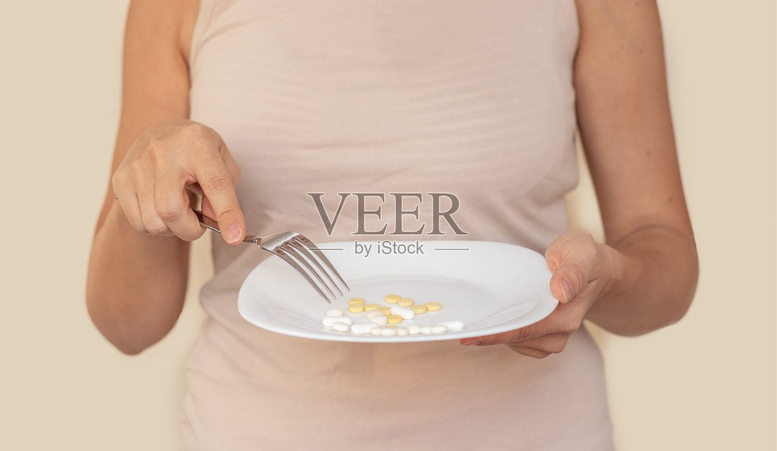 产后减重产后恢复肚腩。年轻的母亲肩上扛着卷尺，手里拿着黄色的苹果或盘子里放着不同的药片，用叉子分开吃。照片摄影图片