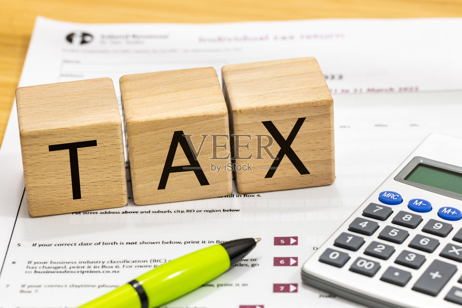 个人新西兰纳税申报单，表格IR3和人手用笔填写文件，用木块写上税务，财务概念照片摄影图片