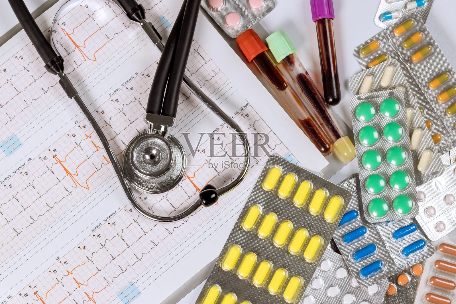 在心脏科医生的办公室里，各种药片和听诊器，包括心电图和听诊器照片摄影图片