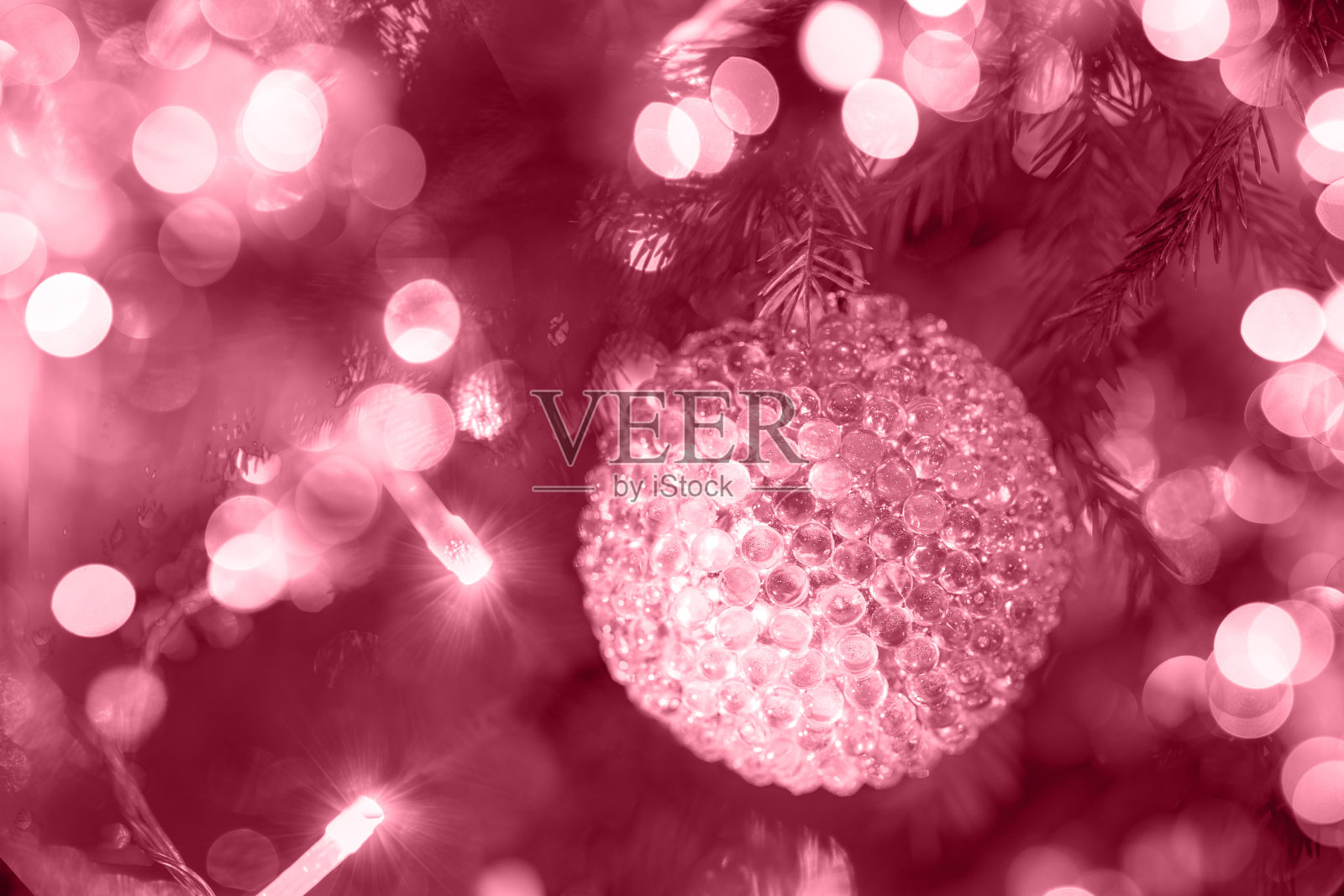 玻璃质感的圣诞球挂在圣诞树上，颜色为2023洋红色。照片摄影图片