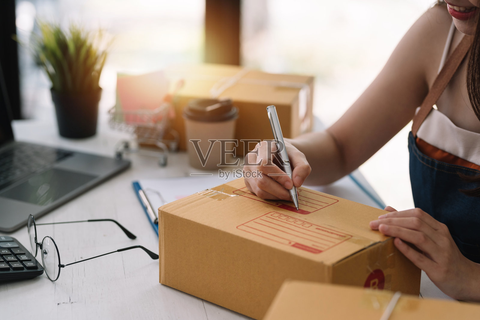 网上销售年轻的亚洲女企业主正在注意客户的地址在包裹盒子上准备交付。照片摄影图片