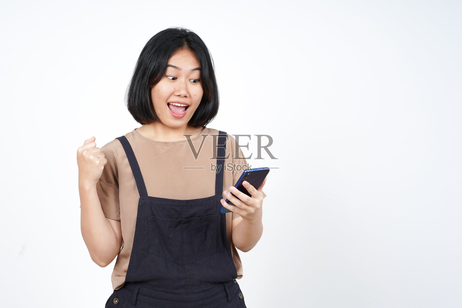 用智能手机与美丽的亚洲女性在白色背景上隔离的庆祝手势照片摄影图片