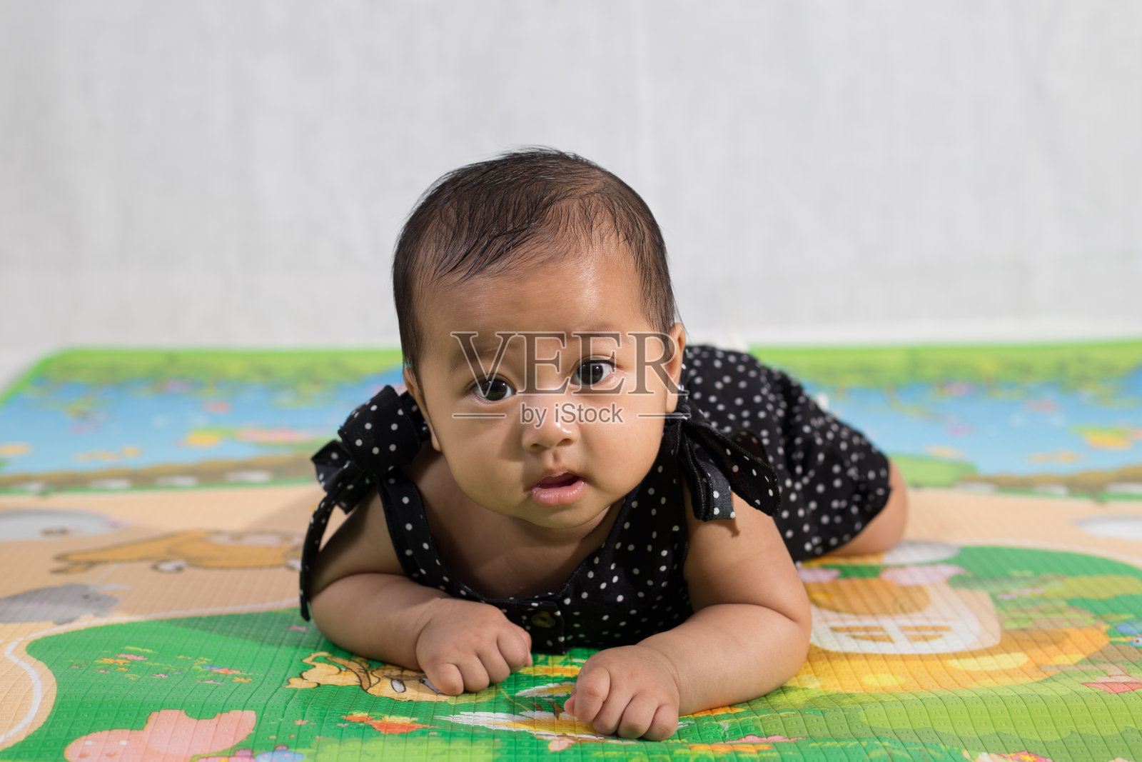 在马来西亚，一名东南亚小女孩坐在彩色儿童垫子上照片摄影图片