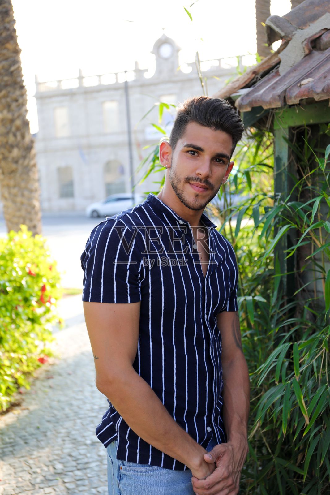 一个穿着条纹衬衫的年轻西班牙男子在花园里摆姿势的特写照片摄影图片