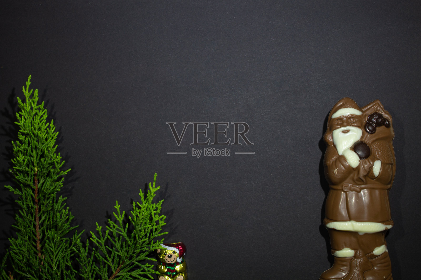 新年照片-圣诞老人由黑白色巧克力和圣诞树与庆祝熊在黑色背景照片摄影图片