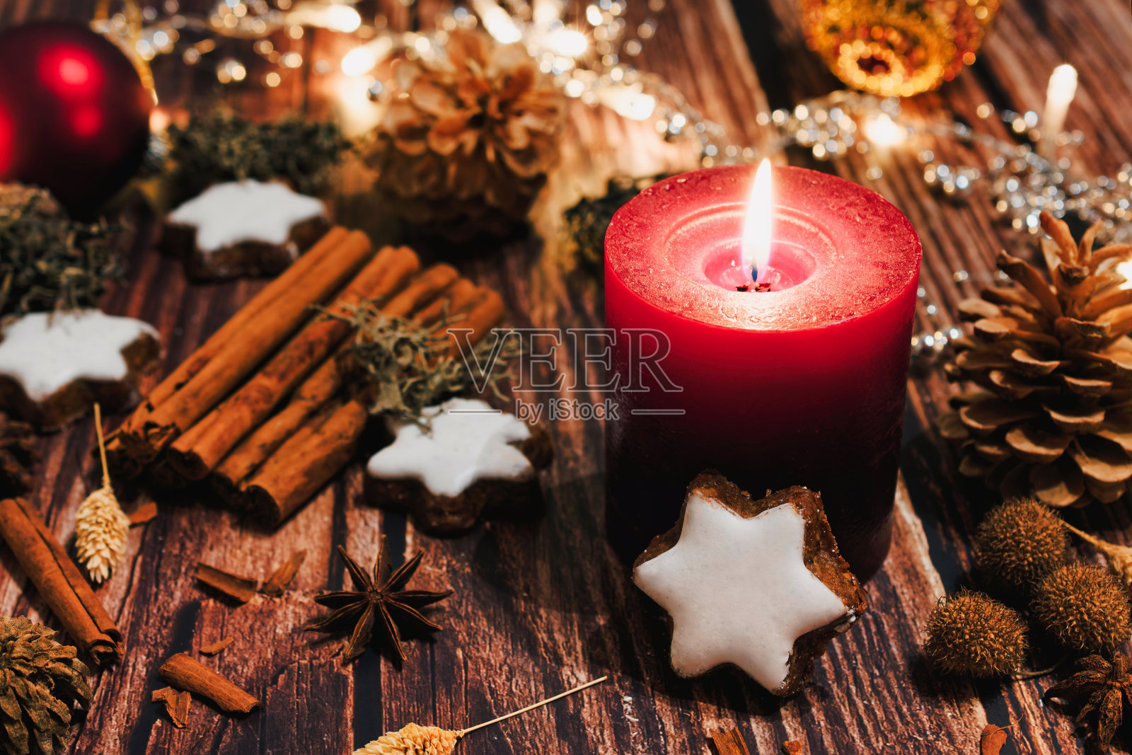 圣诞装饰用红色的蜡烛和肉桂星星和一串灯。照片摄影图片