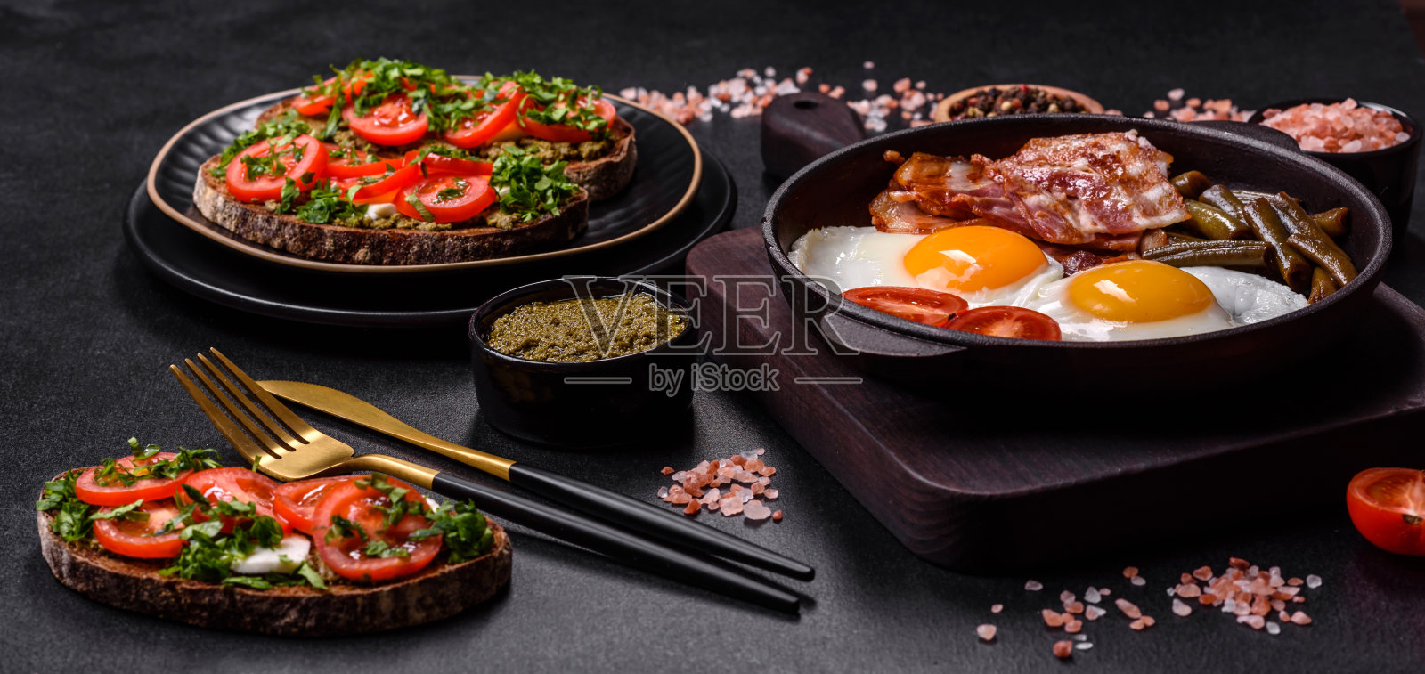 美味的早餐包括鸡蛋、熏肉、豆类、西红柿，还有香料和香草照片摄影图片