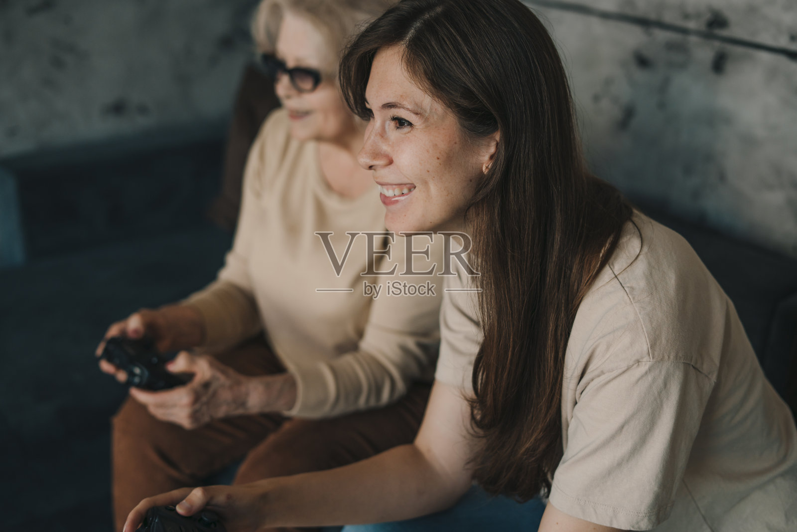 年迈的奶奶带着女儿玩游戏机，欢欣胜利，爱好无穷。笑得很开心。闲暇时间与人的观念照片摄影图片