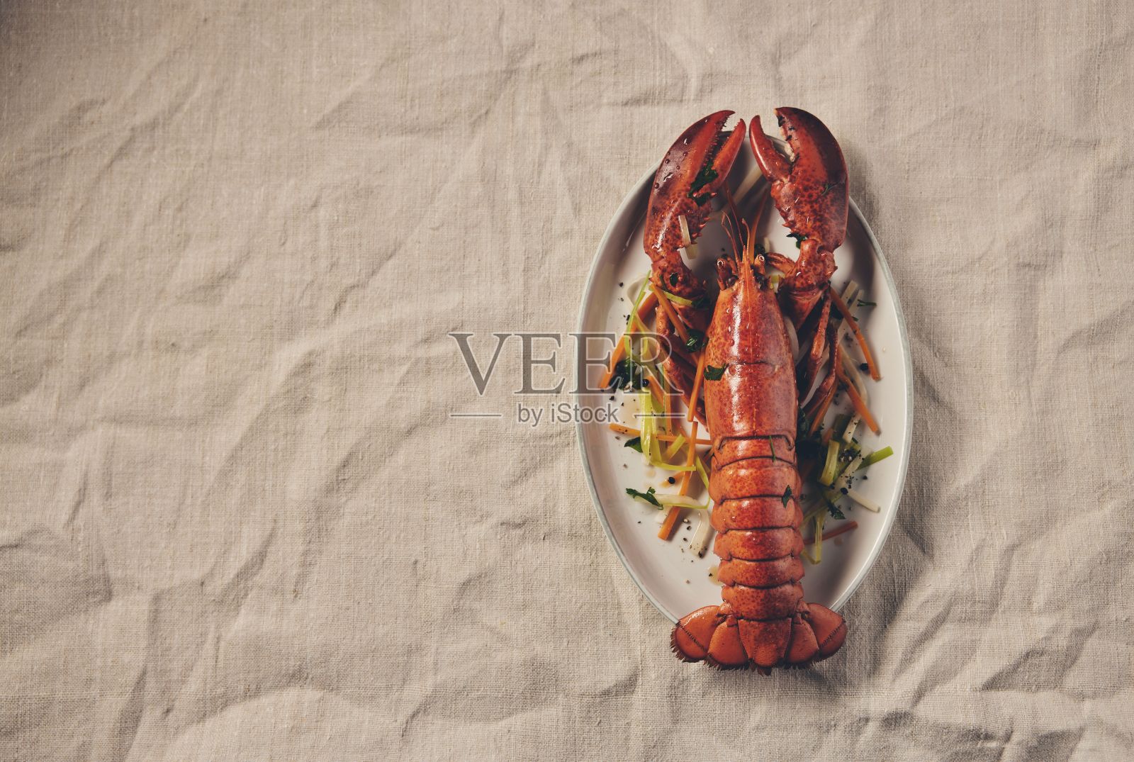 俯视图，煮熟的龙虾被放在白色盘子里，蔬菜放在亚麻布桌布上照片摄影图片