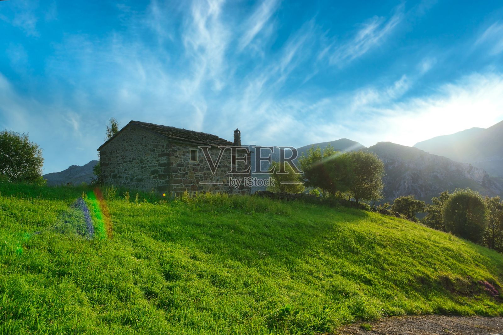 西班牙坎塔布里亚，蔚蓝多云的天空下，郁郁葱葱的乡村山上的小石屋照片摄影图片