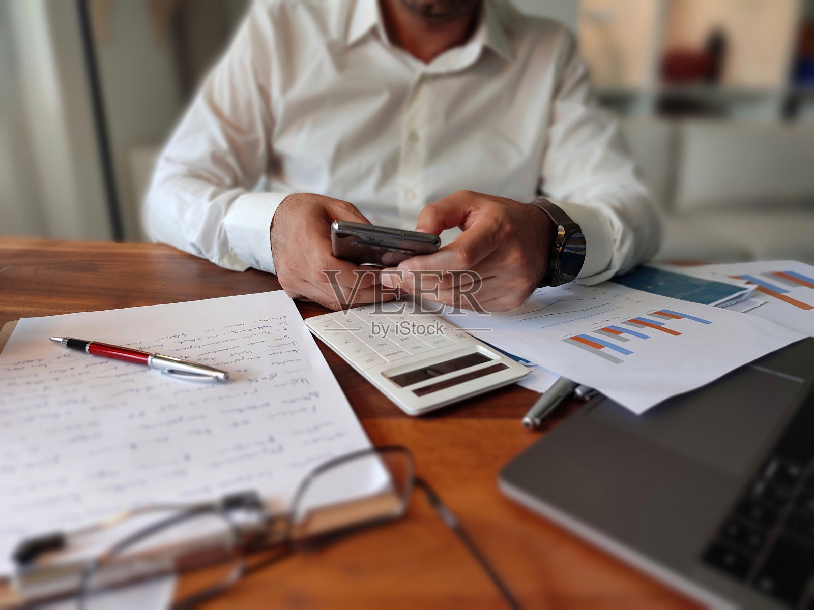 男性手持智能手机。商人在咖啡馆工作时使用笔记本电脑和平板电脑。移动应用程序或物联网概念。数字时代的现代生活方式照片摄影图片