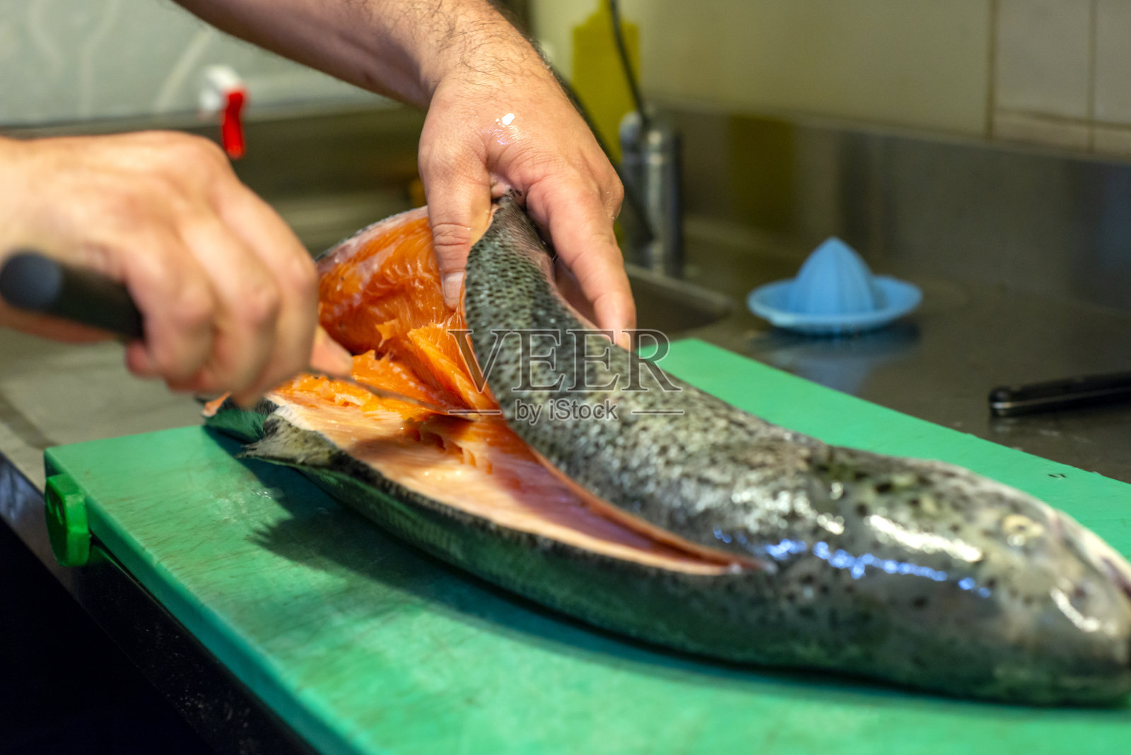 寿司师傅在寿司架上切新鲜三文鱼。厨师在专业厨房切三文鱼片。照片摄影图片