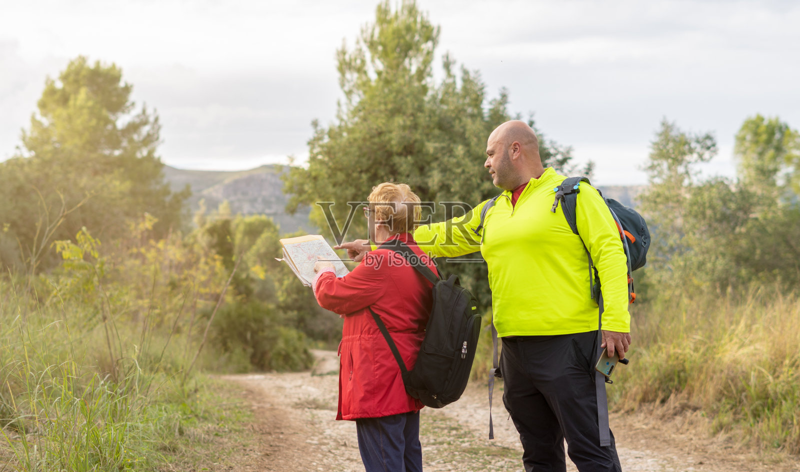 中年男子带着老年妇女带着地图，一边徒步旅行一边找路照片摄影图片