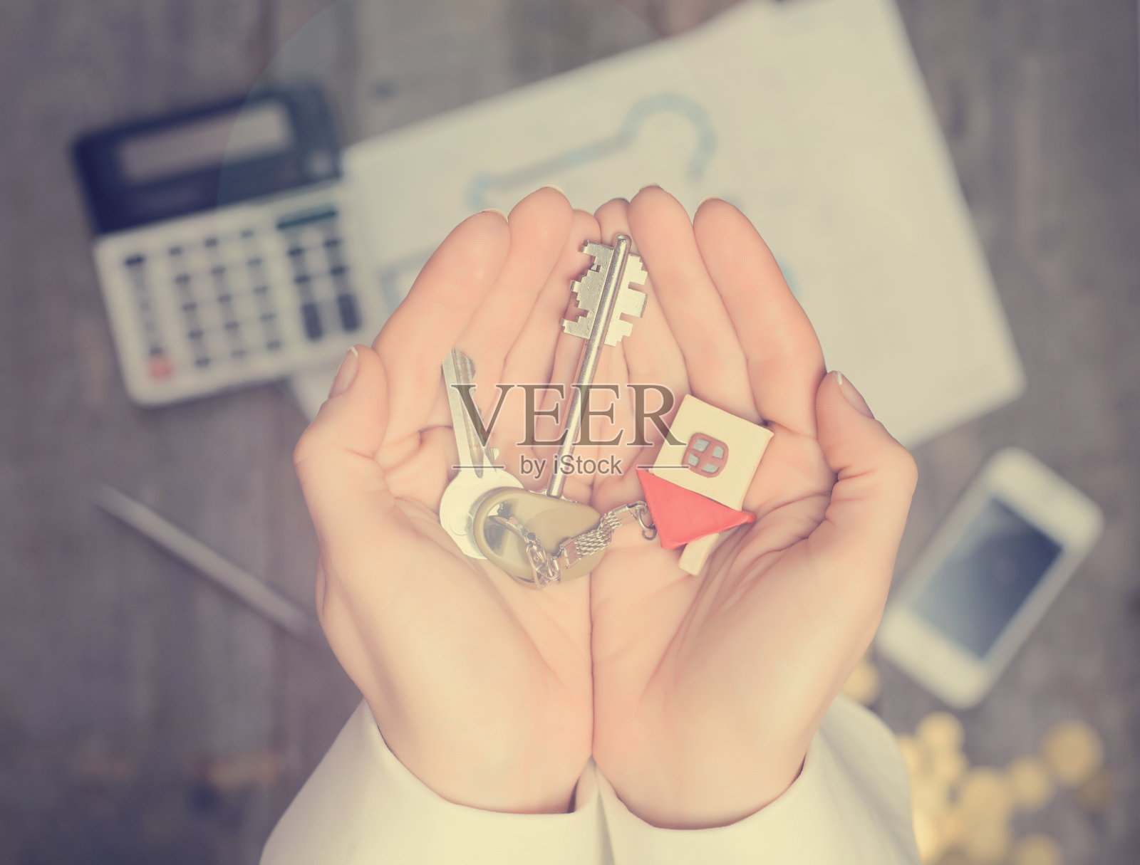 房地产经纪人交出一个房子的钥匙，桌面与工具，木材色板和电脑的背景，俯视图照片摄影图片