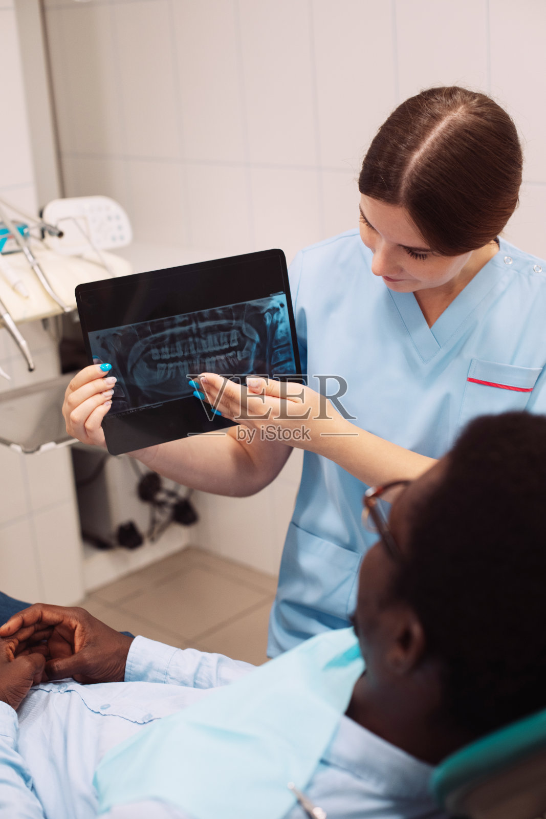 年轻的女牙医医生展示牙科治疗结果，展示牙齿x光片照片摄影图片