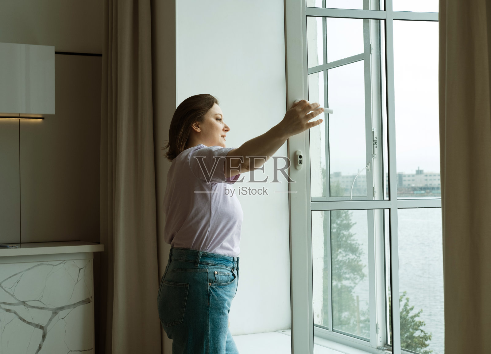 清晨，一个胖胖的女人打开窗户，享受着新鲜的空气照片摄影图片