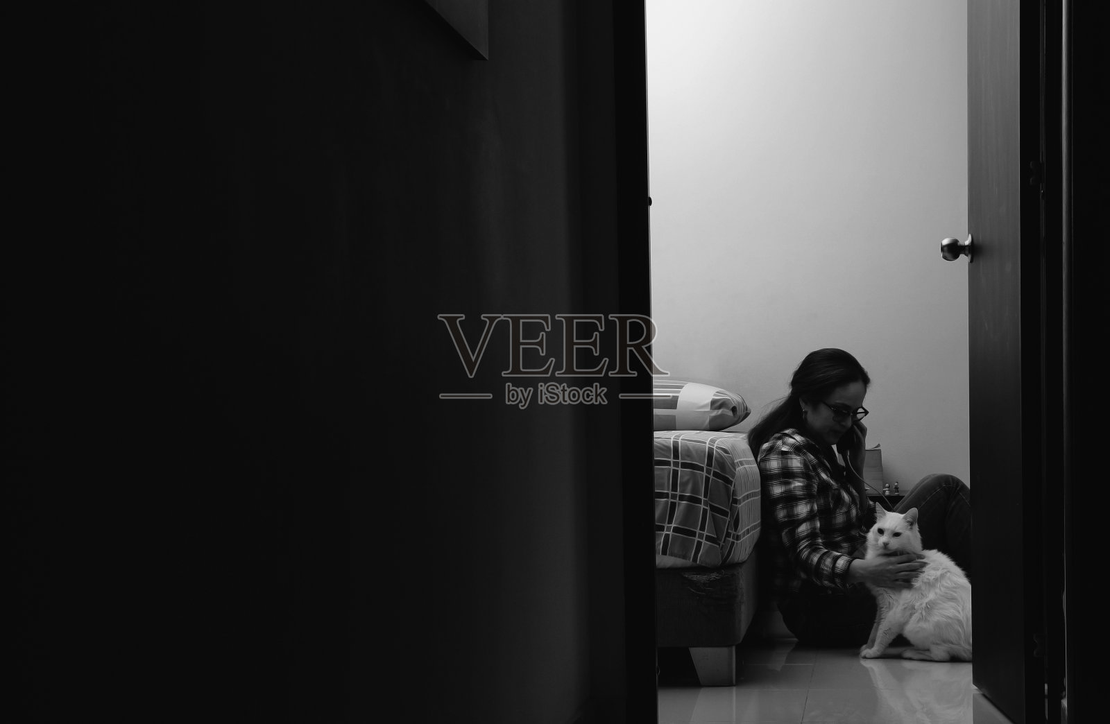 沮丧的女子坐在地板上，靠在床上打电话照片摄影图片