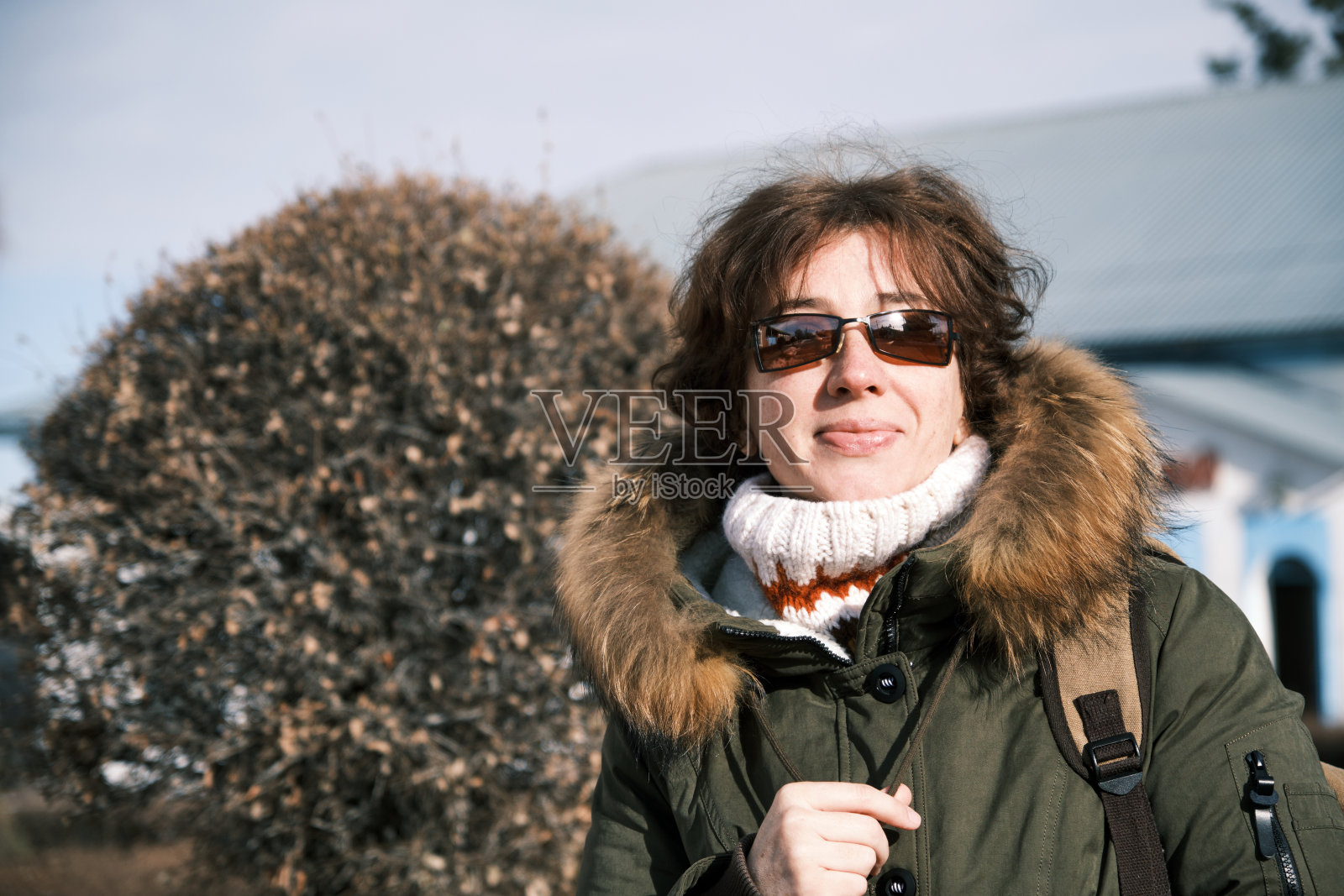 冬日里，一位女游客在阳光明媚的小镇街道上四处张望照片摄影图片