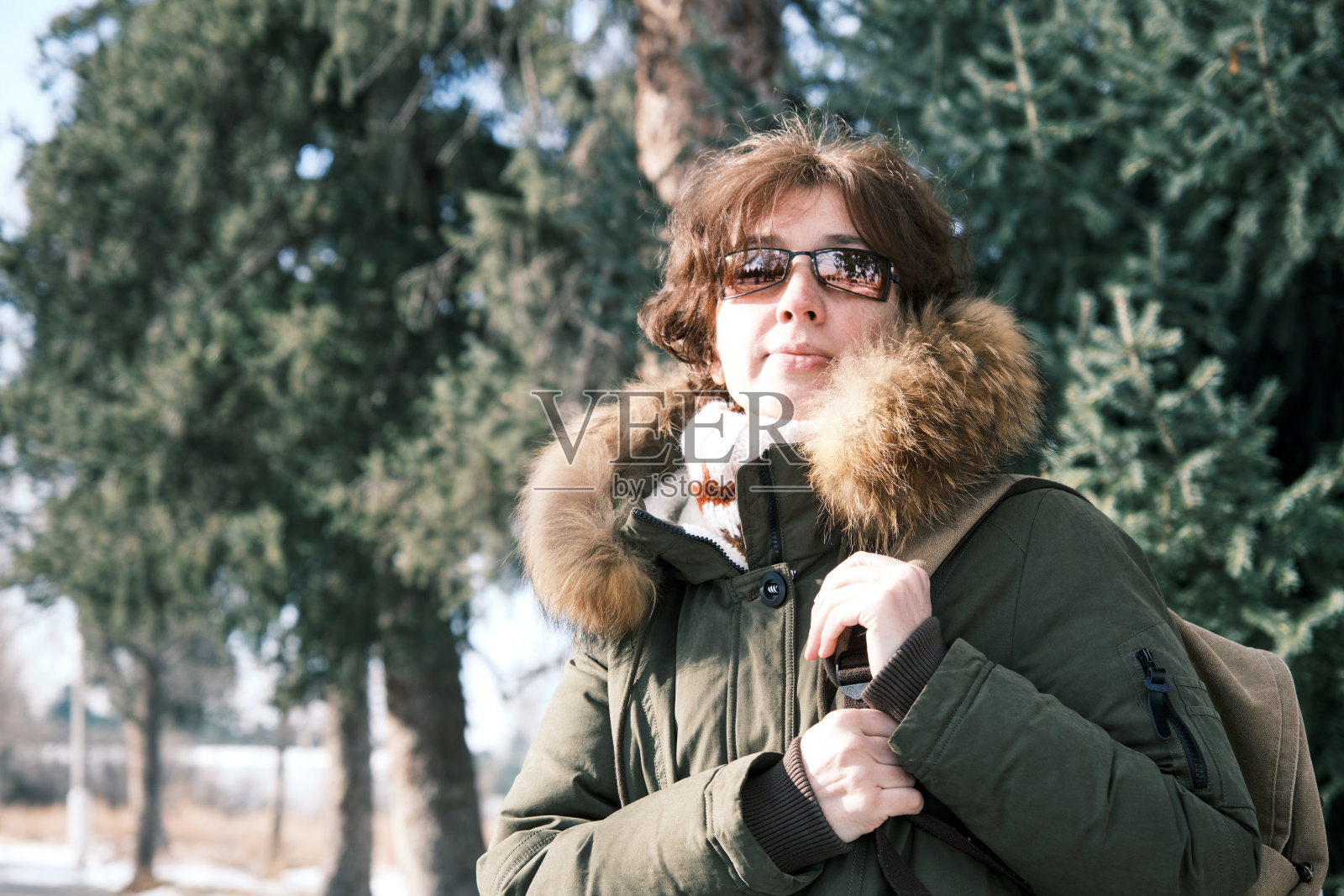 冬日里，一位女游客在阳光明媚的小镇街道上四处张望照片摄影图片