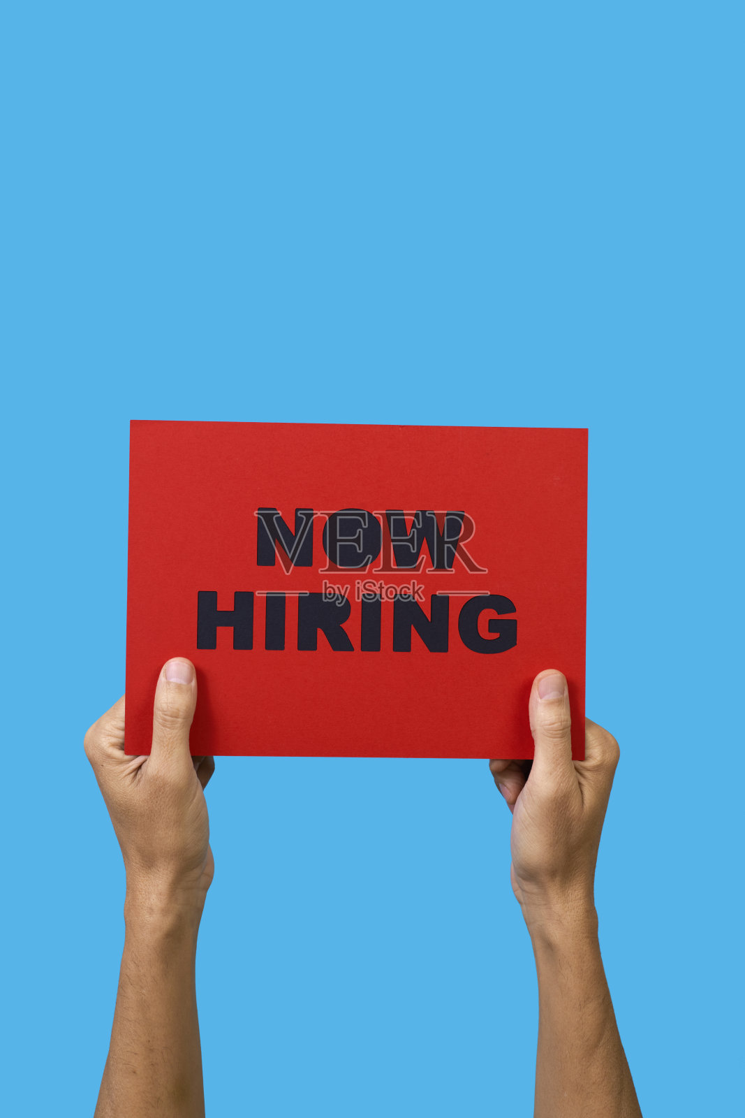 一名男子举着一个牌子，上面写着“现在招聘”照片摄影图片