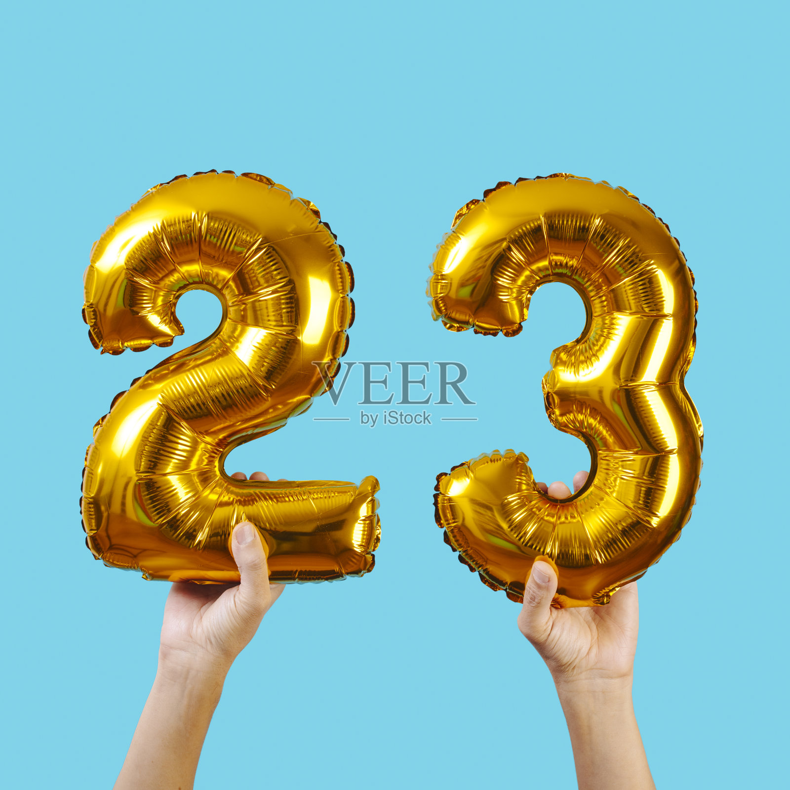 手持两个气球，组成数字23照片摄影图片