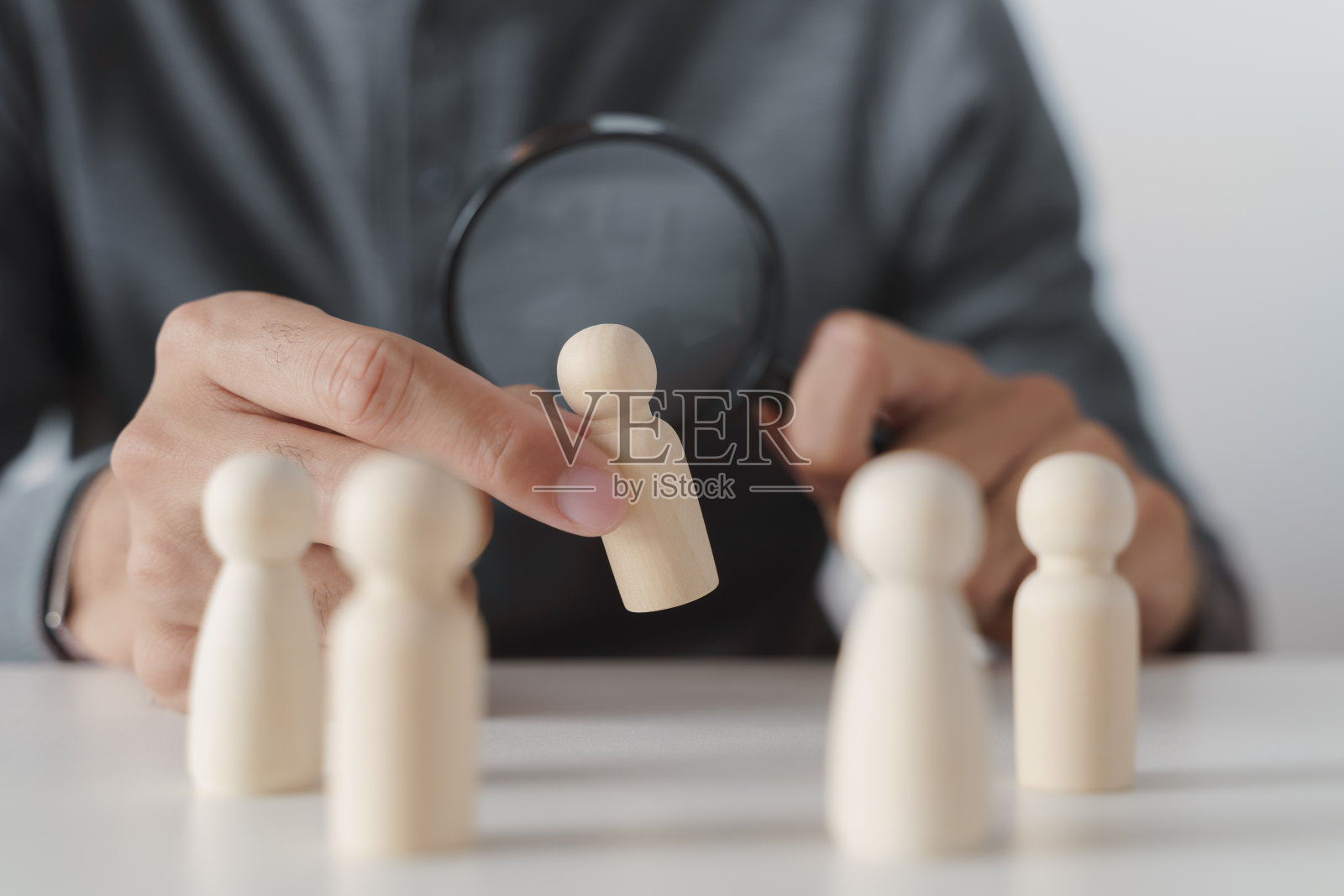 手握放大镜注视木头人。求职，人力资源，招聘概念照片摄影图片